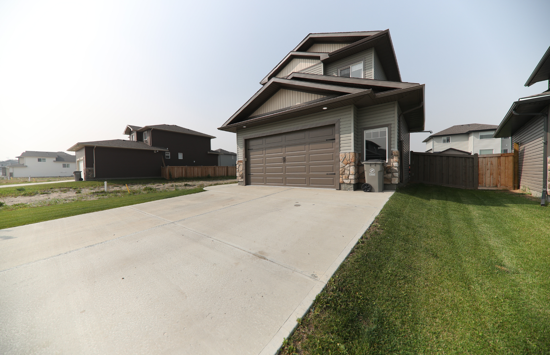 Suburban house with two-car garage, concrete driveway, and neatly trimmed lawn