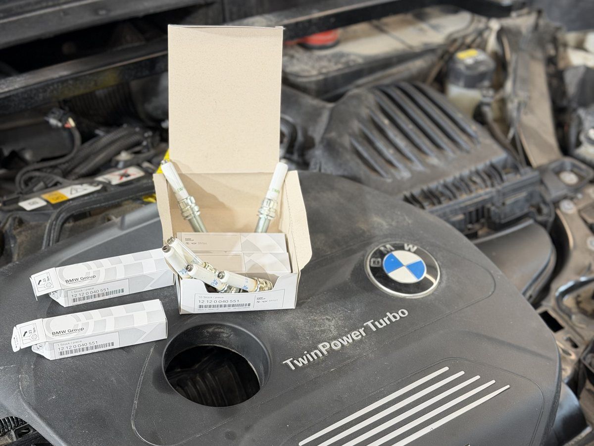 New spark plugs in their boxes on an engine cover in the No Name Auto Repair shop in Norwood, MA