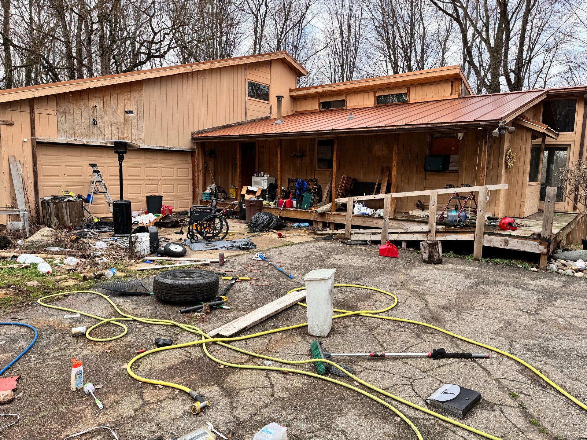 A house with a porch and a lot of junk in front of it.