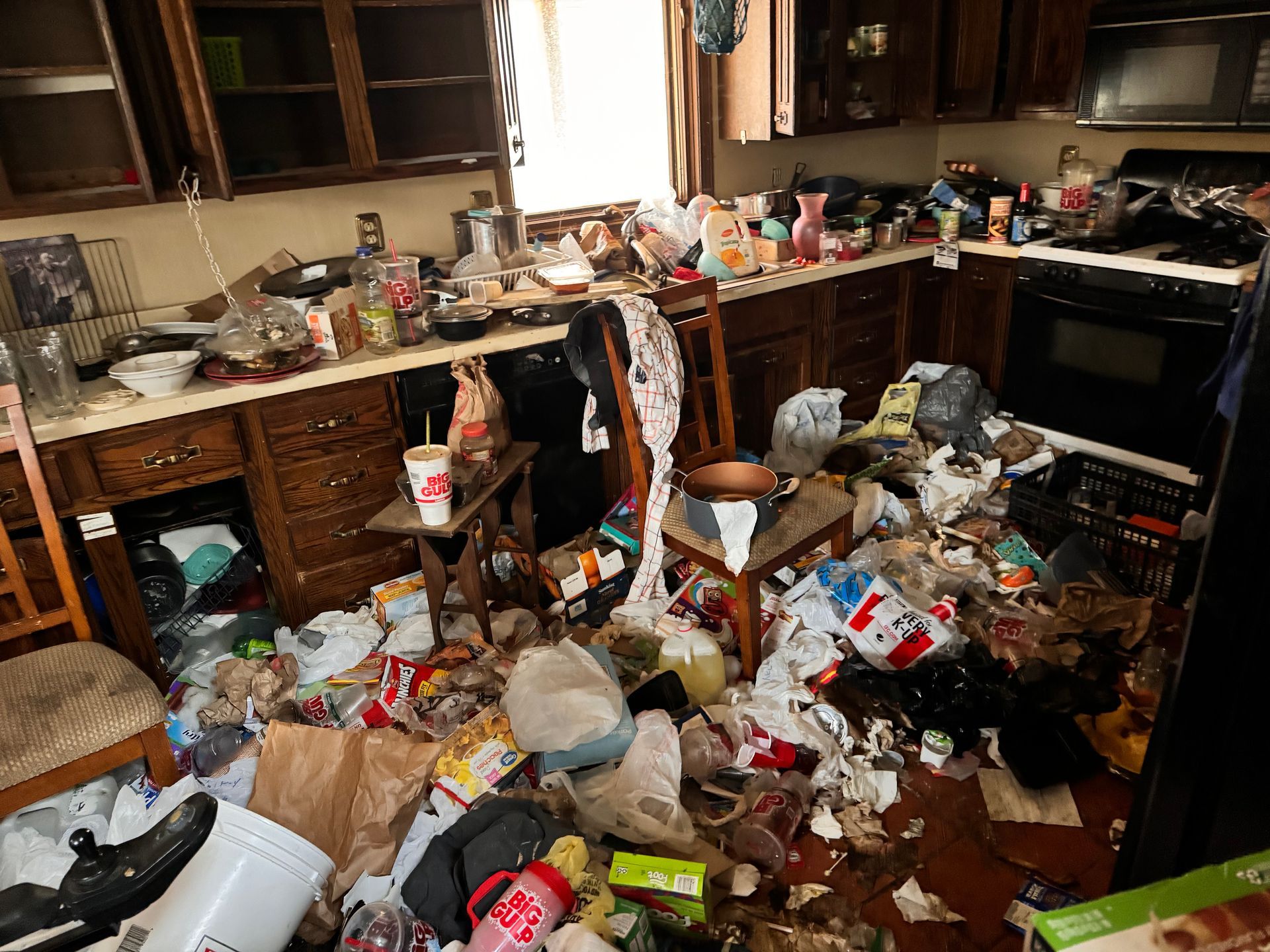 A kitchen with a lot of trash on the floor and counters.