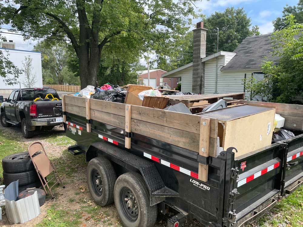 A dumpster filled with trash is parked in front of a house.