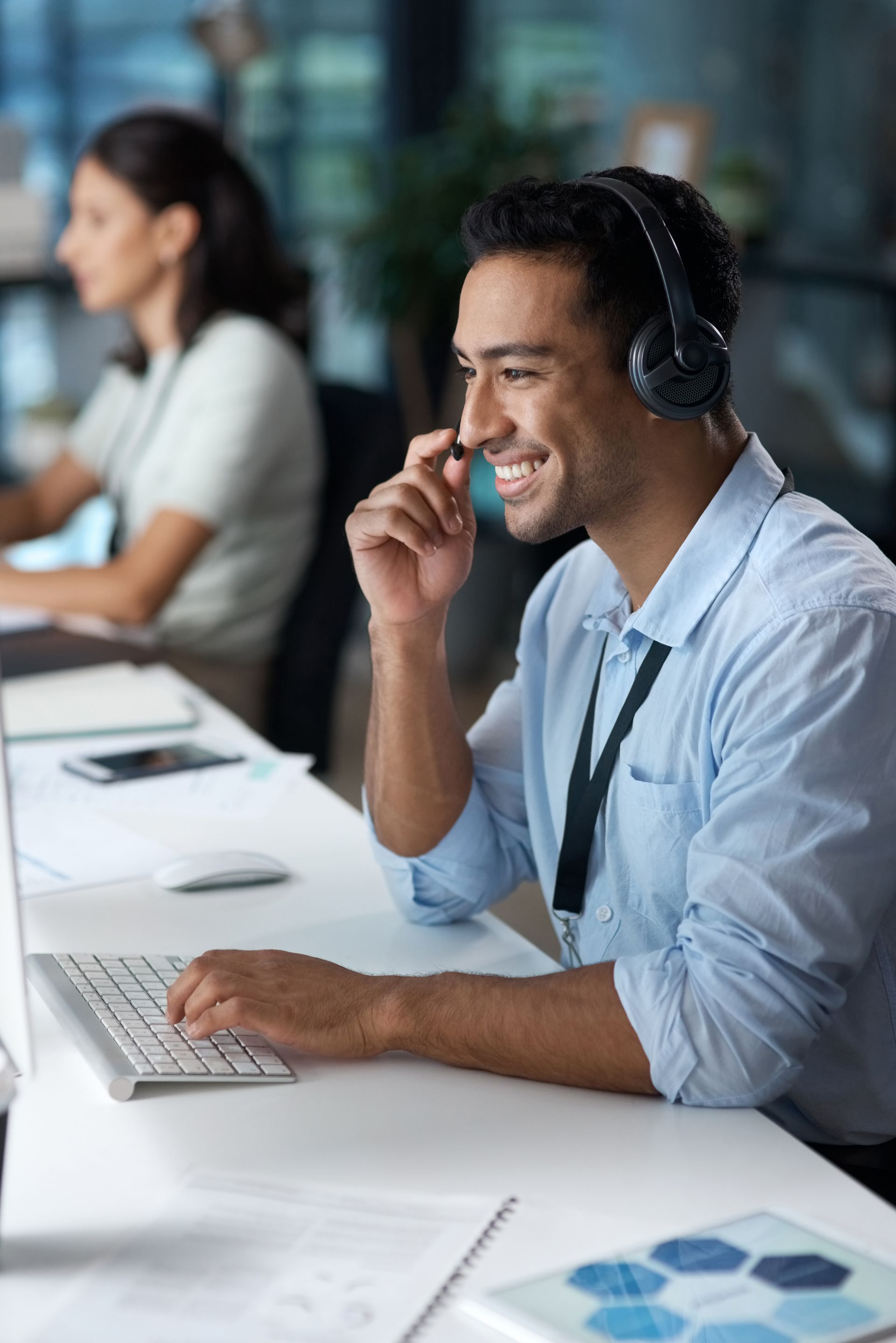 A man wearing headphones is sitting at a desk in front of a computer.