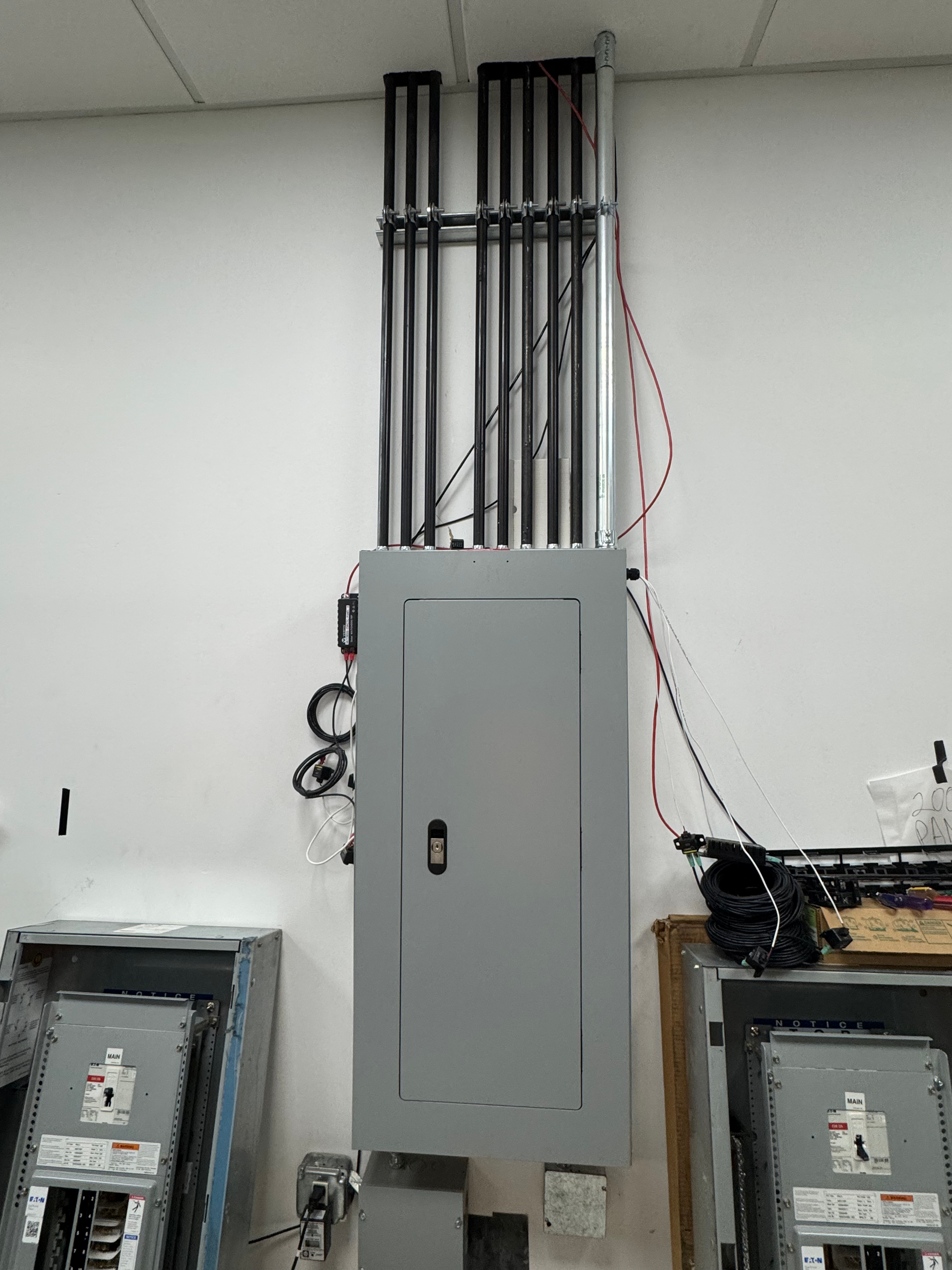 Electrical service panels with conduit and wiring mounted on a white wall.