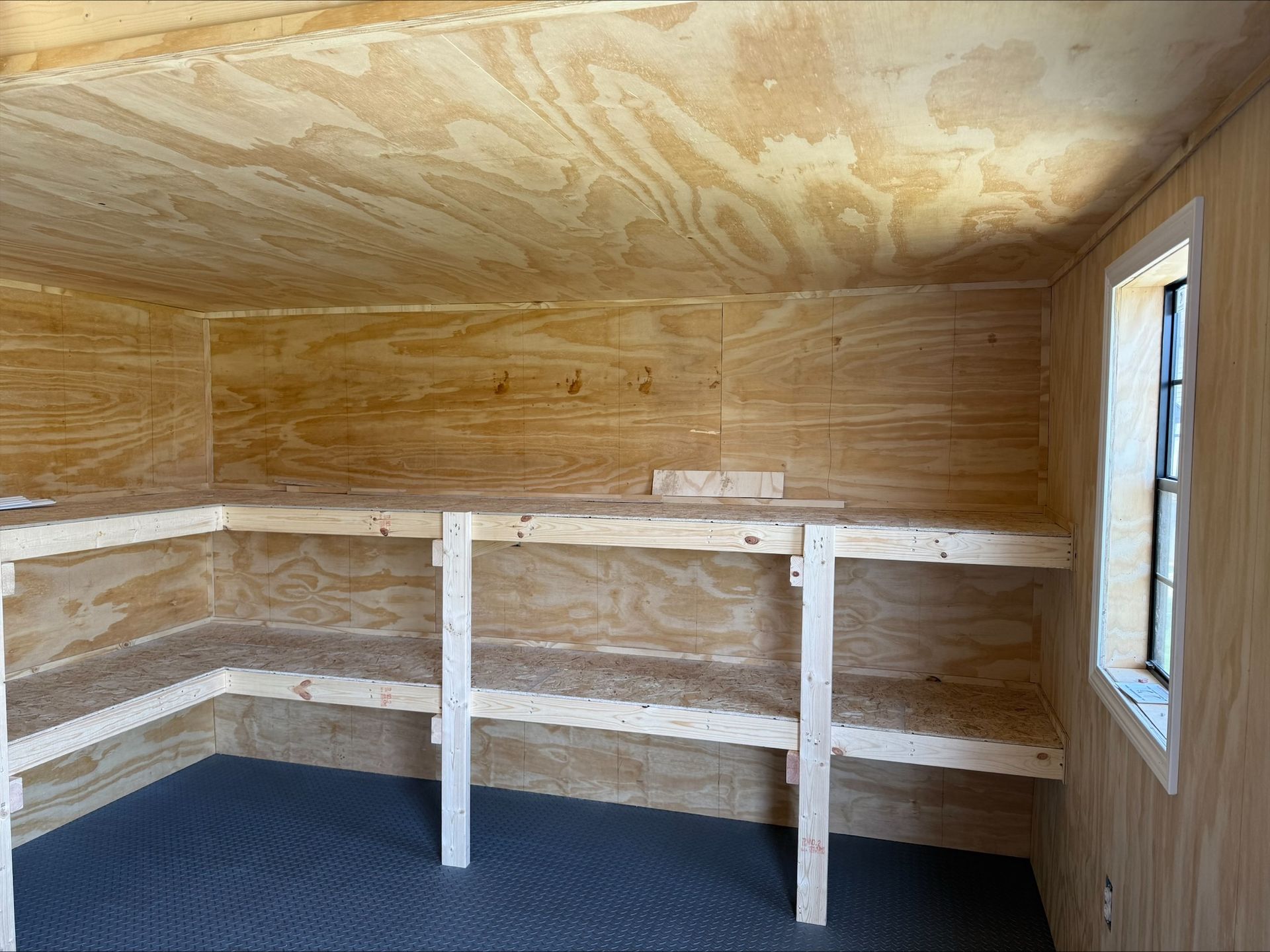 Wood-paneled storage room with white shelves and a small window, empty except for a dark floor mat.