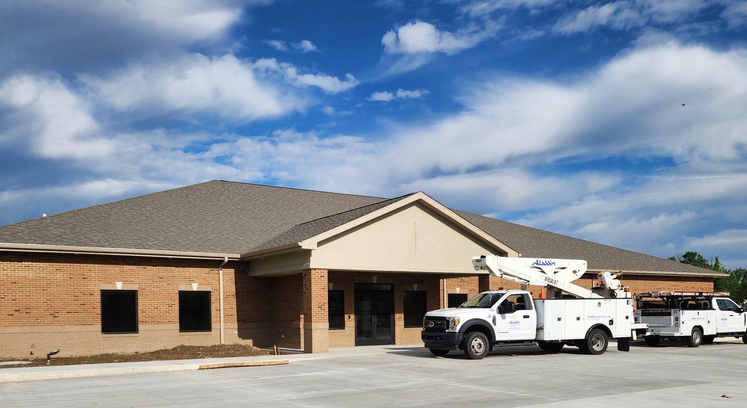 Brick building under blue sky with two white utility trucks parked outside