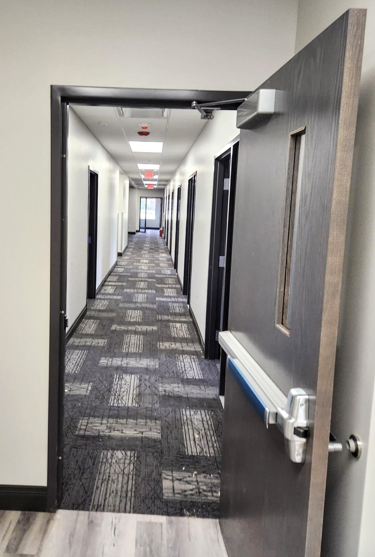 Open hotel hallway with patterned carpet and a partially open door in the foreground