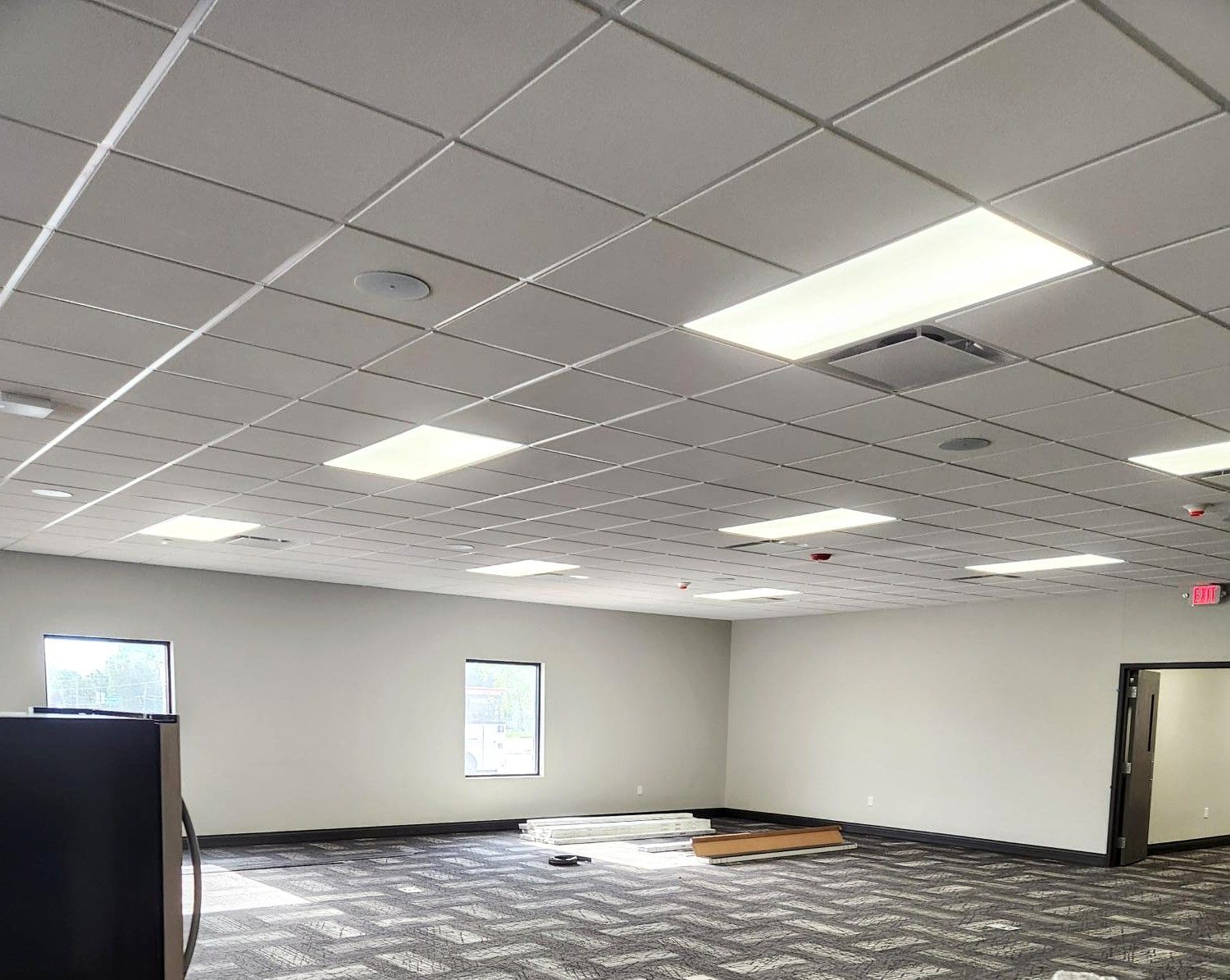 Empty office space with carpet tiles, drop ceiling, and fluorescent lights