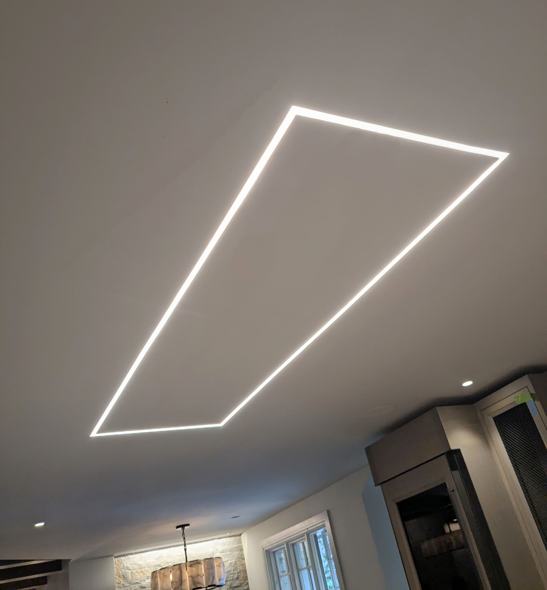 Modern living room ceiling with a glowing rectangular LED light fixture