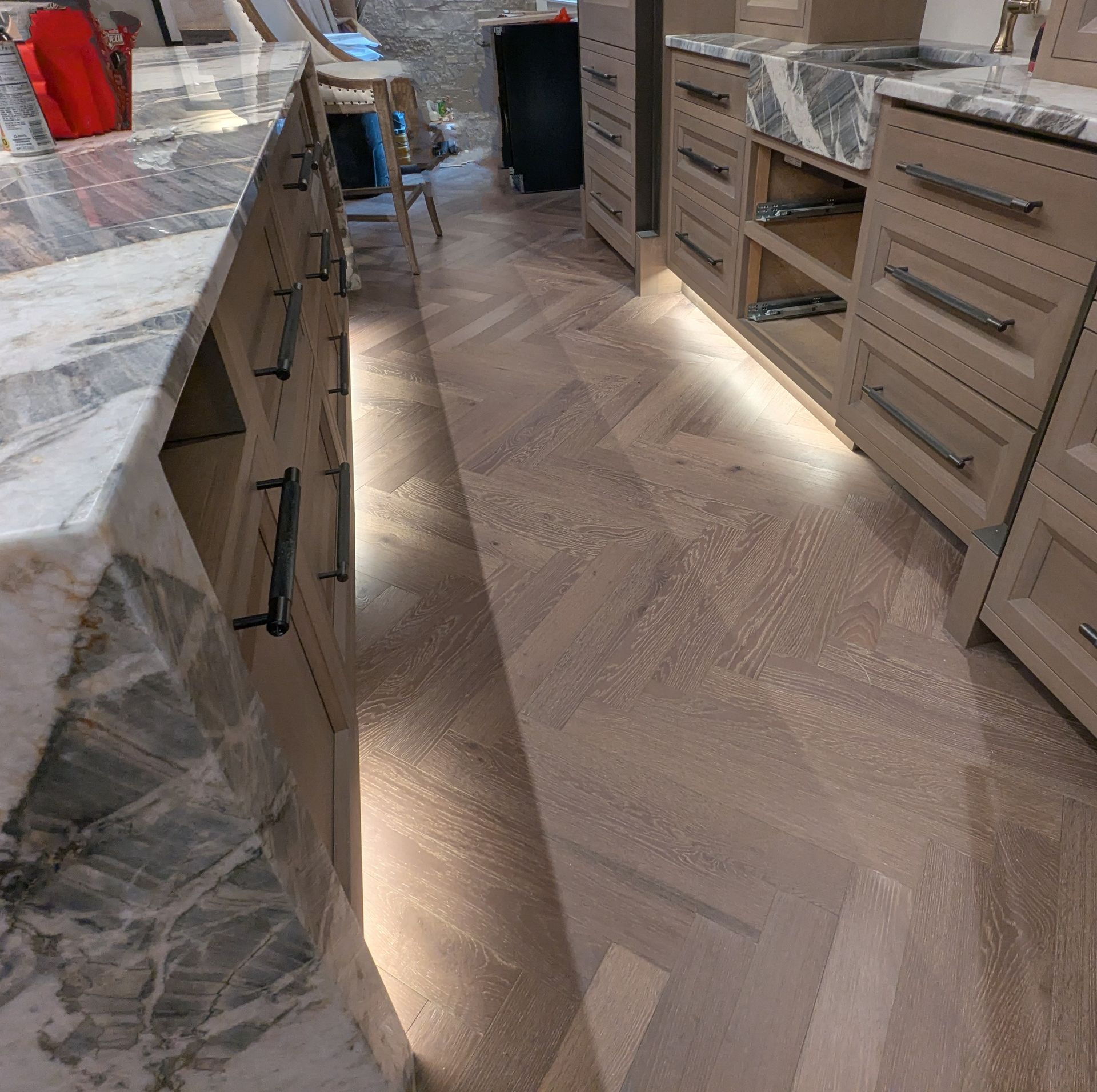 Kitchen remodel with light wood cabinets, marble countertops, and a herringbone floor pattern