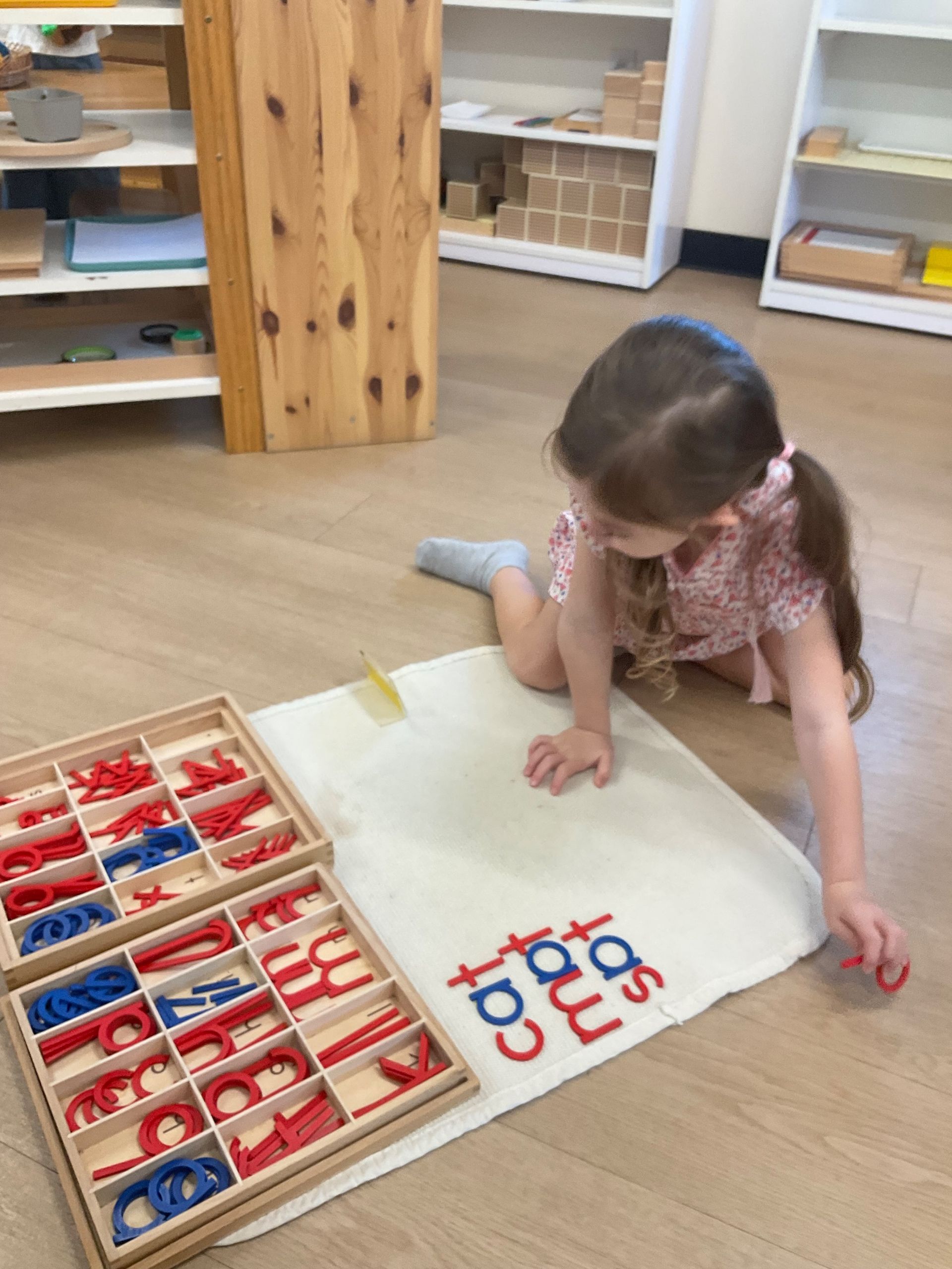 Child working with the moveable alphabet on a working mat.