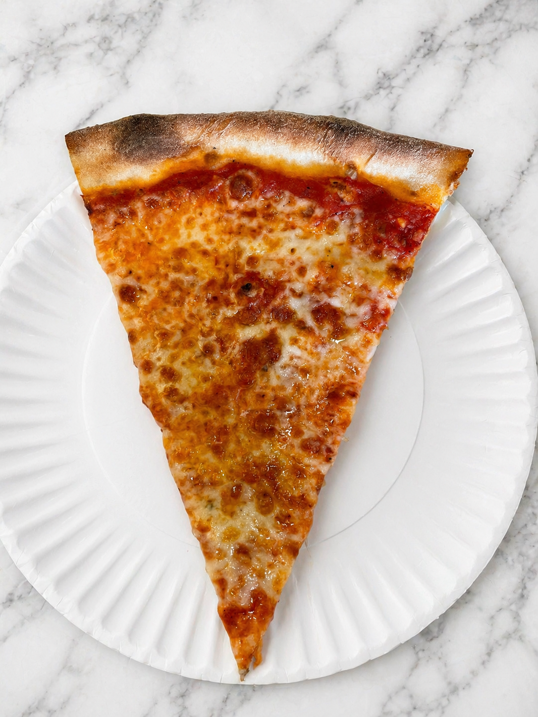 Slice of cheese pizza on a white paper plate