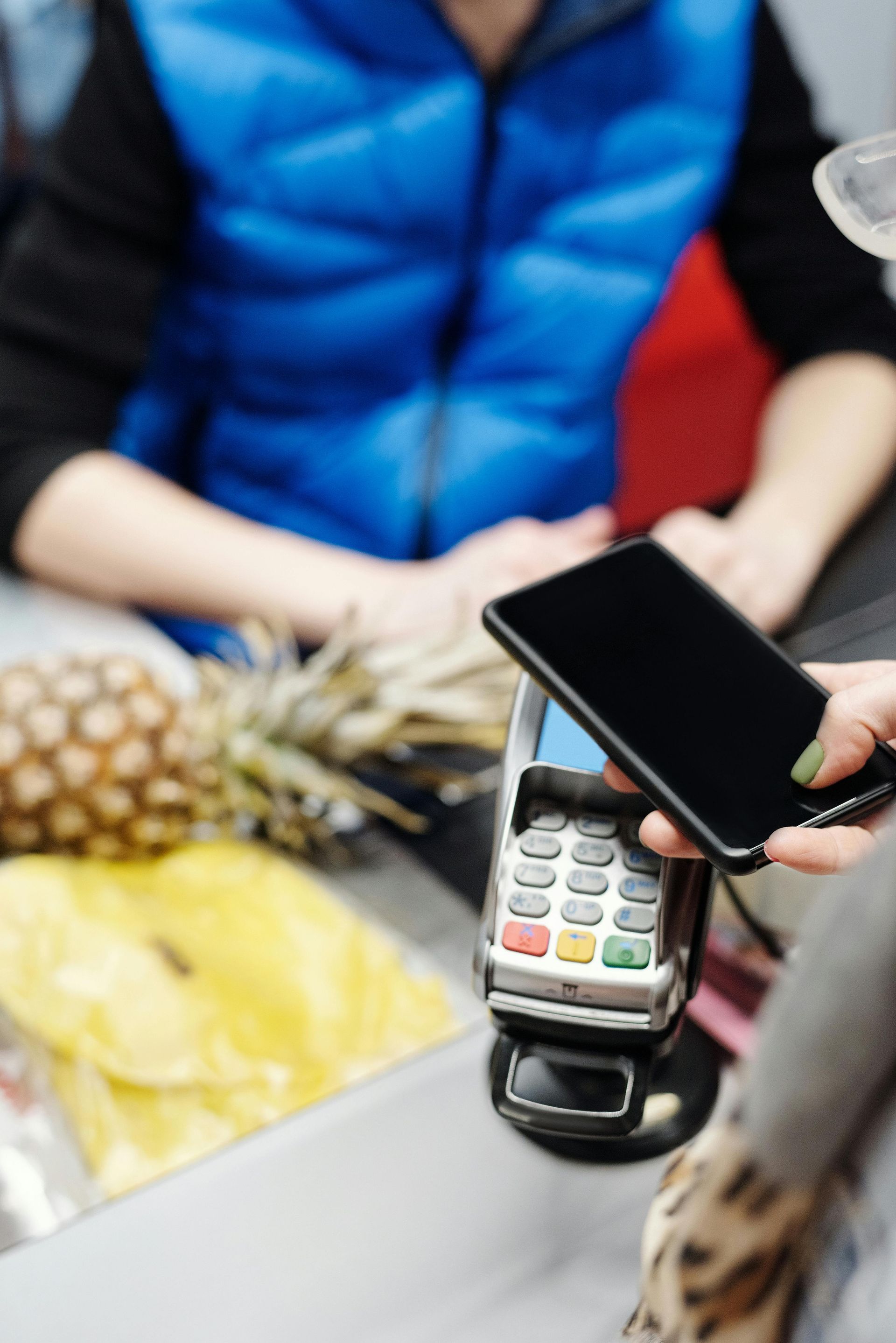 A person is holding a cell phone in front of a credit card machine.