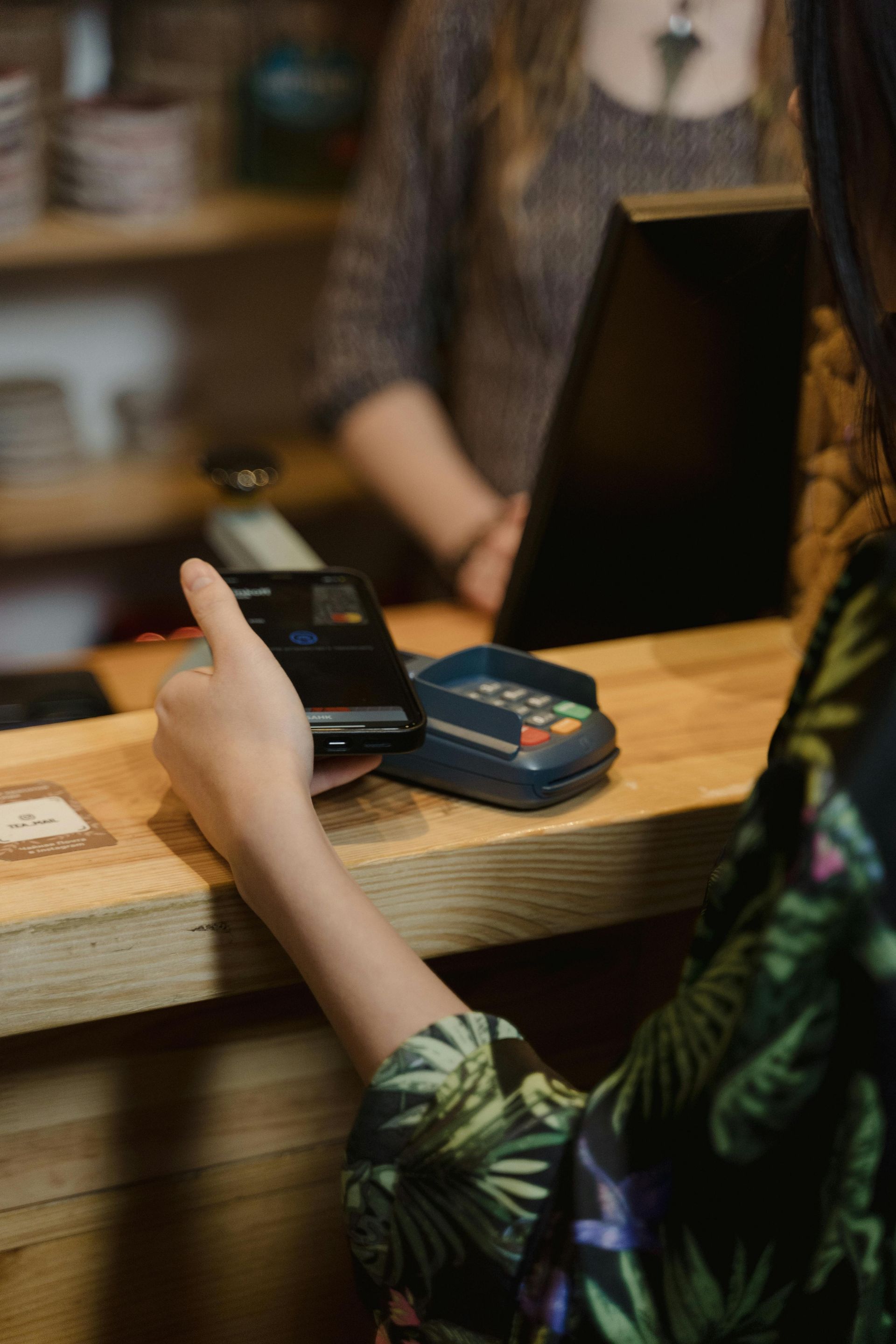 A woman is using a credit card to pay at a counter.