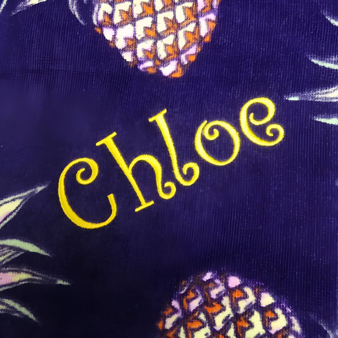 A Close Up of the Name Chloe on a Purple Background With Pineapples — Central West Trophies & Embroidery In Orange, NSW