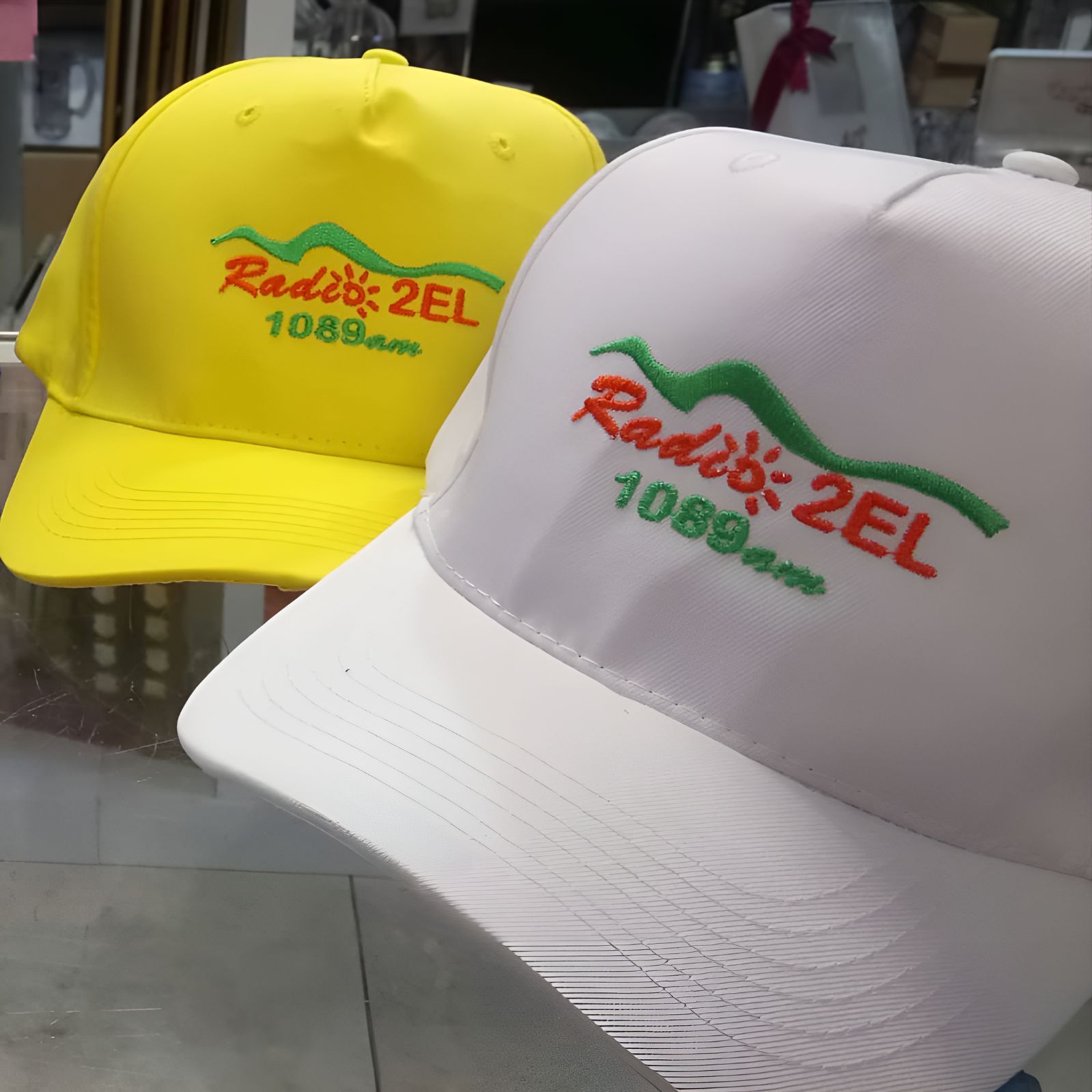 A Yellow Hat and a White Hat Both Say Radio 2el — Central West Trophies & Embroidery In Orange, NSW