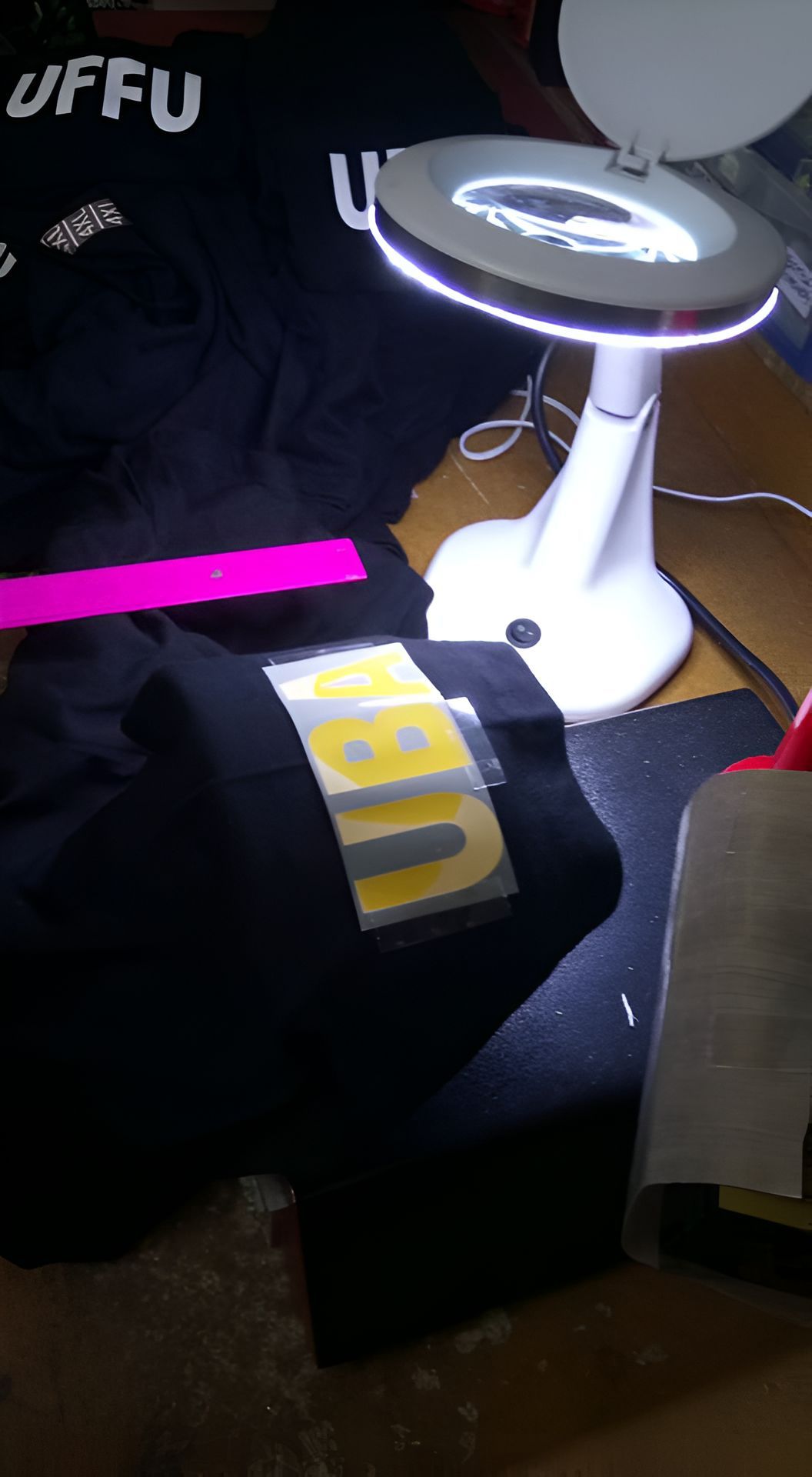 A Magnifying Glass is Sitting on a Table Next to a Black Shirt — Central West Trophies & Embroidery In Orange, NSW