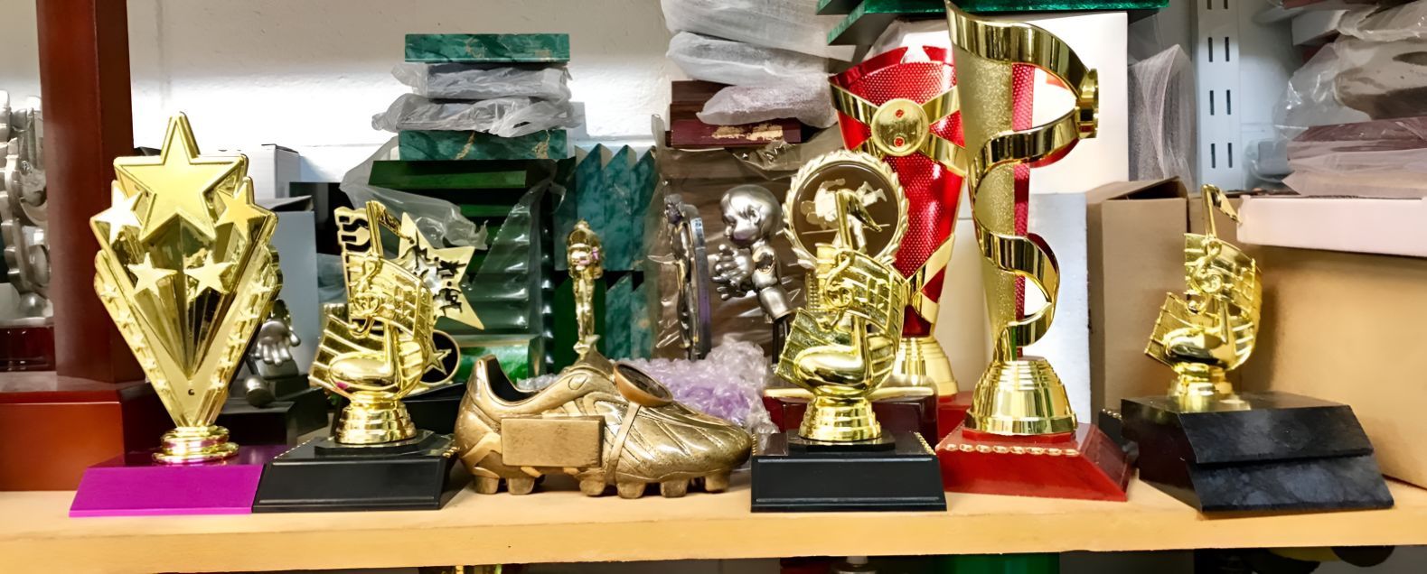 A Bunch of Trophies Are Sitting on a Wooden Shelf — Central West Trophies & Embroidery In Orange, NSW