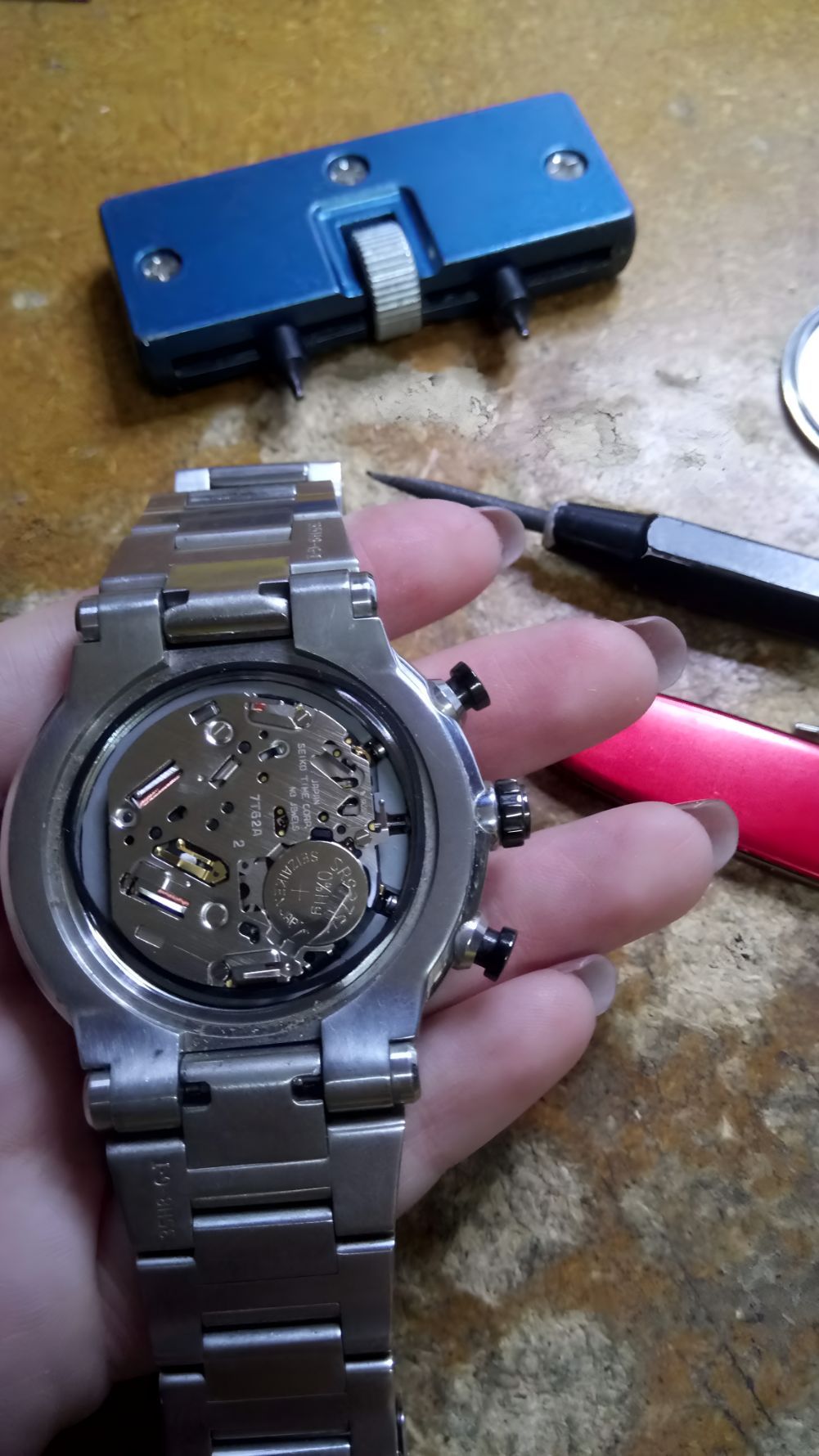 A Person is Holding a Watch With the Back Removed — Central West Trophies & Embroidery In Orange, NSW