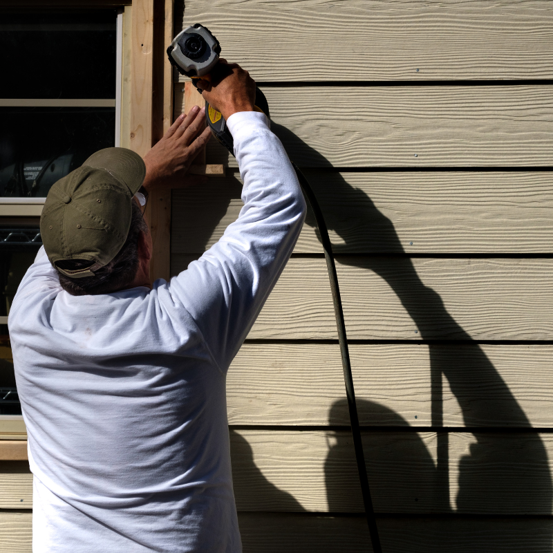 A man is working on a window with a drill