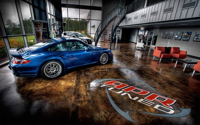 Blue sports car in a modern showroom with polished floors and lounge seating at APR in Opelika