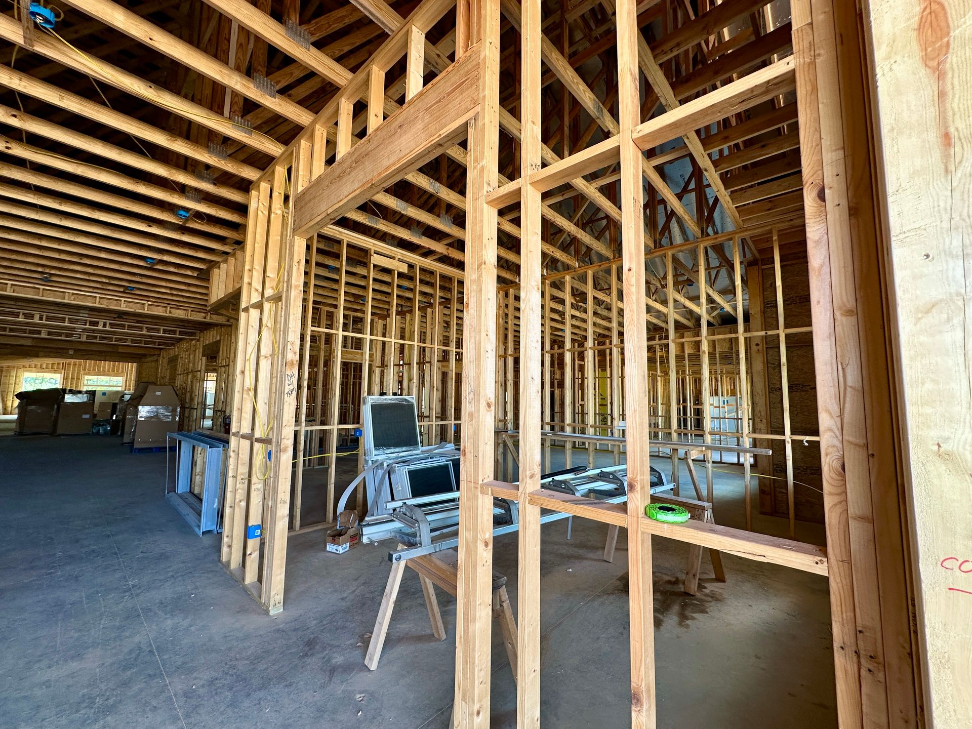 Interior framing of a building under construction, with wooden beams, tools, and an open interior space.