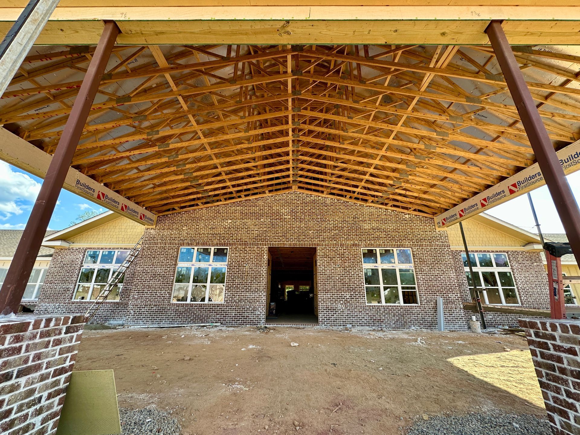 Brick building under construction with exposed wooden roof supports.