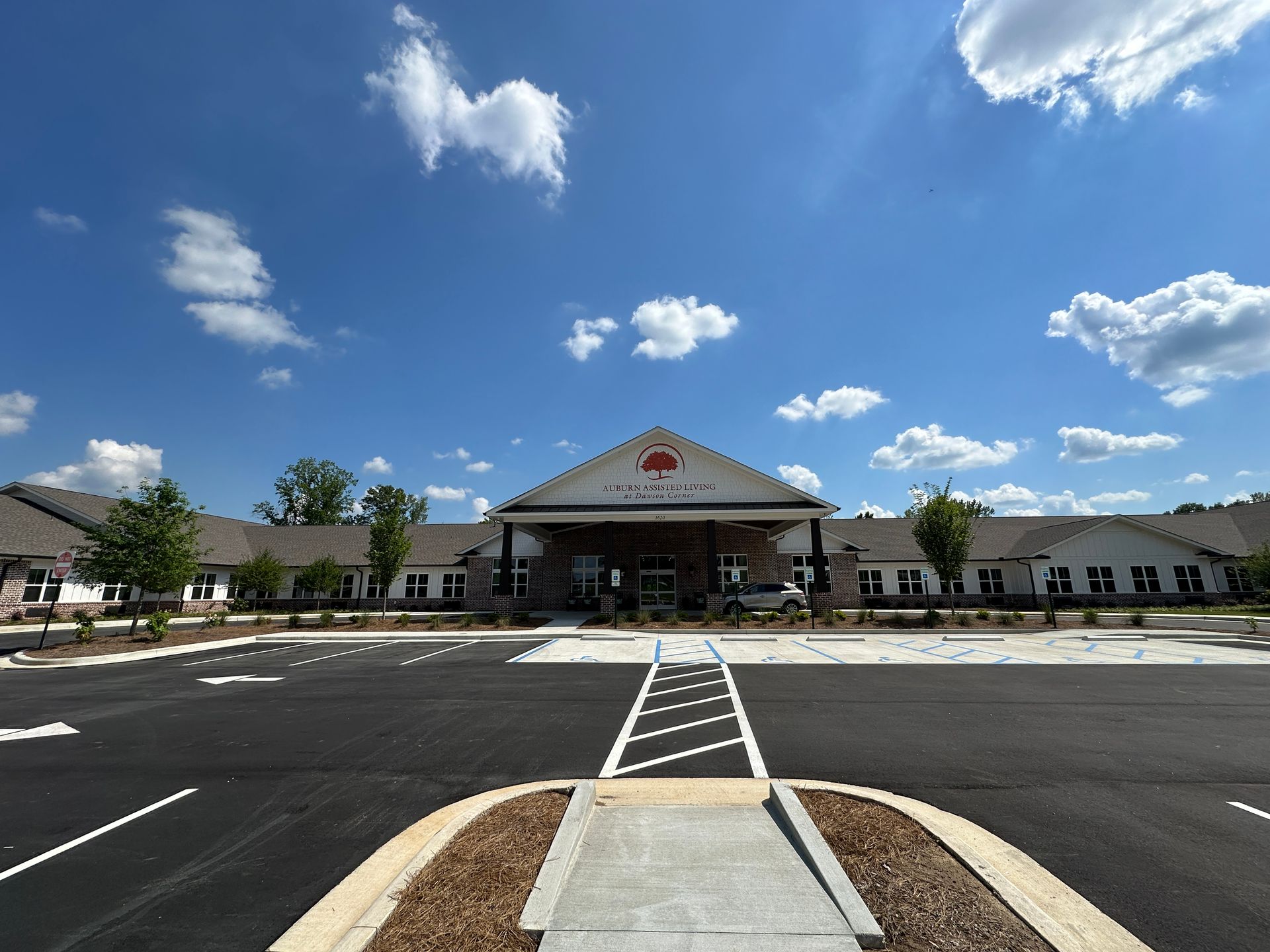 Front view of a large building with a covered entrance and empty parking lot under a blue sky