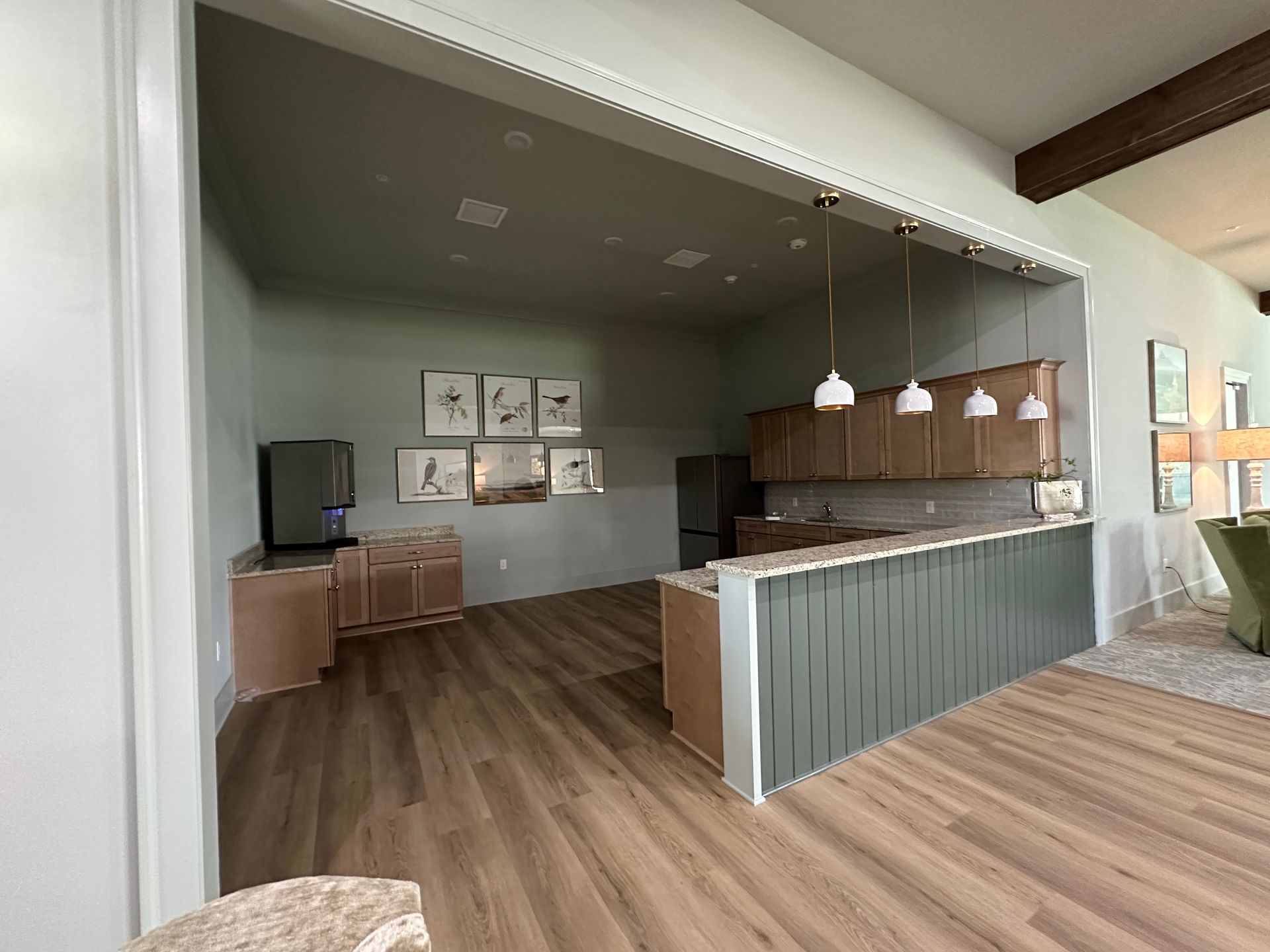 Empty modern café counter with wood floors, green paneling, and pendant lights