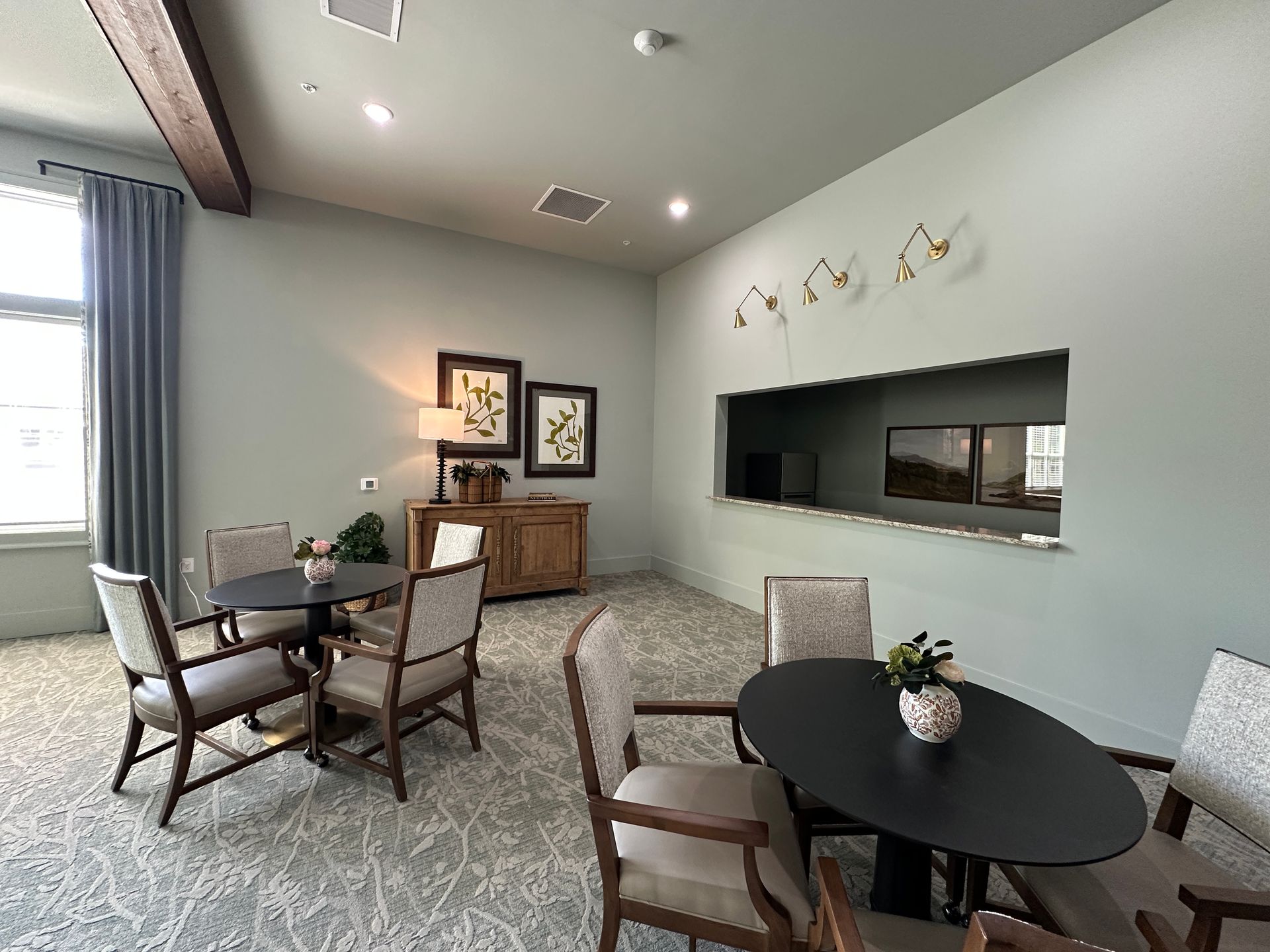 Modern waiting room with gray walls, lounge chairs, round tables, and a reception desk.