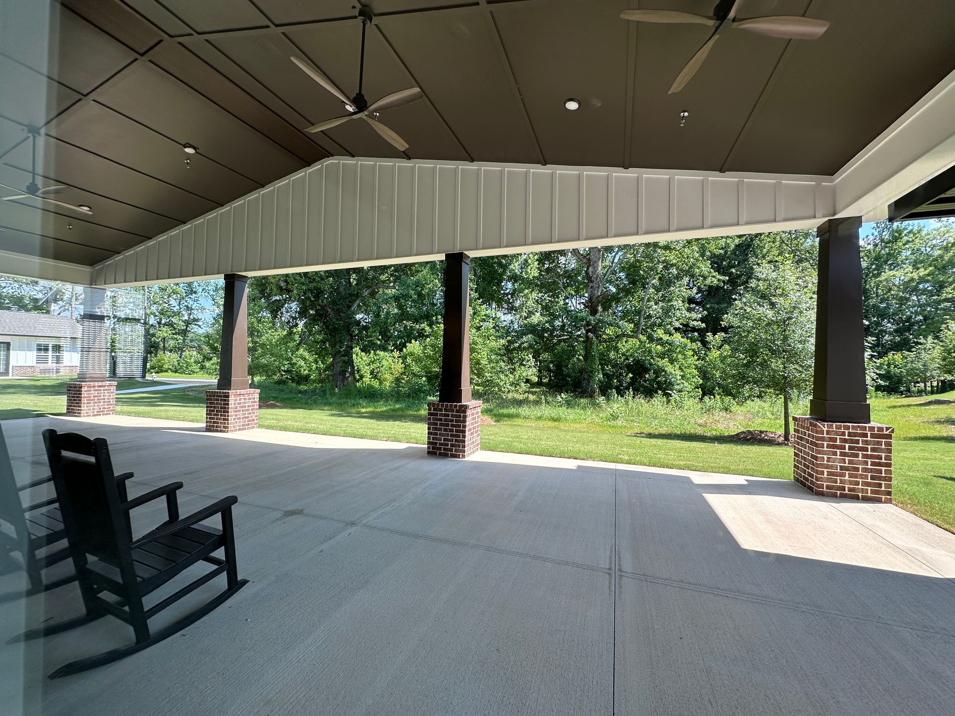 Covered patio with rocking chair overlooking a grassy park and trees