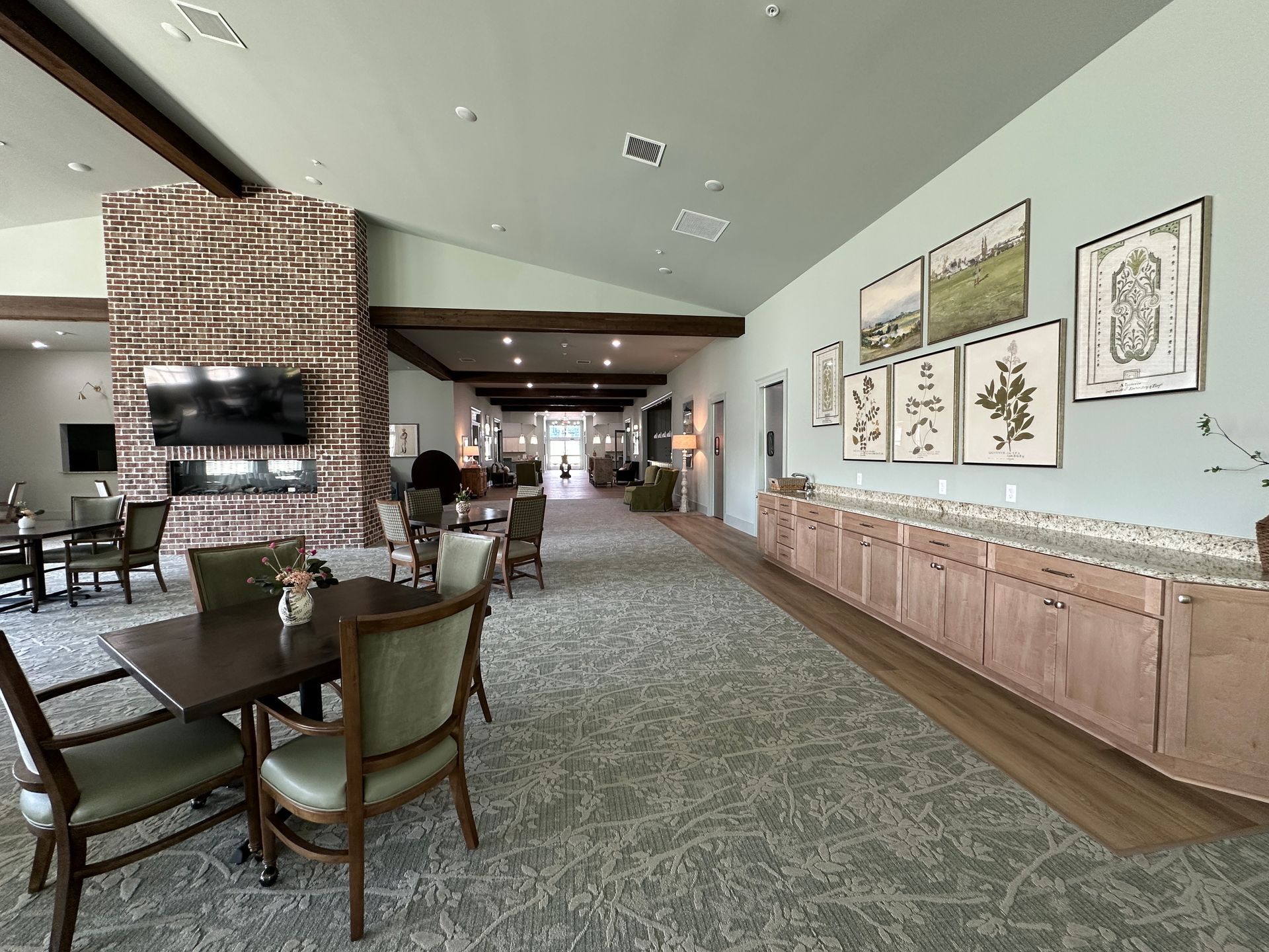 Hotel lobby lounge with fireplace, seating area, patterned carpet, and framed wall art
