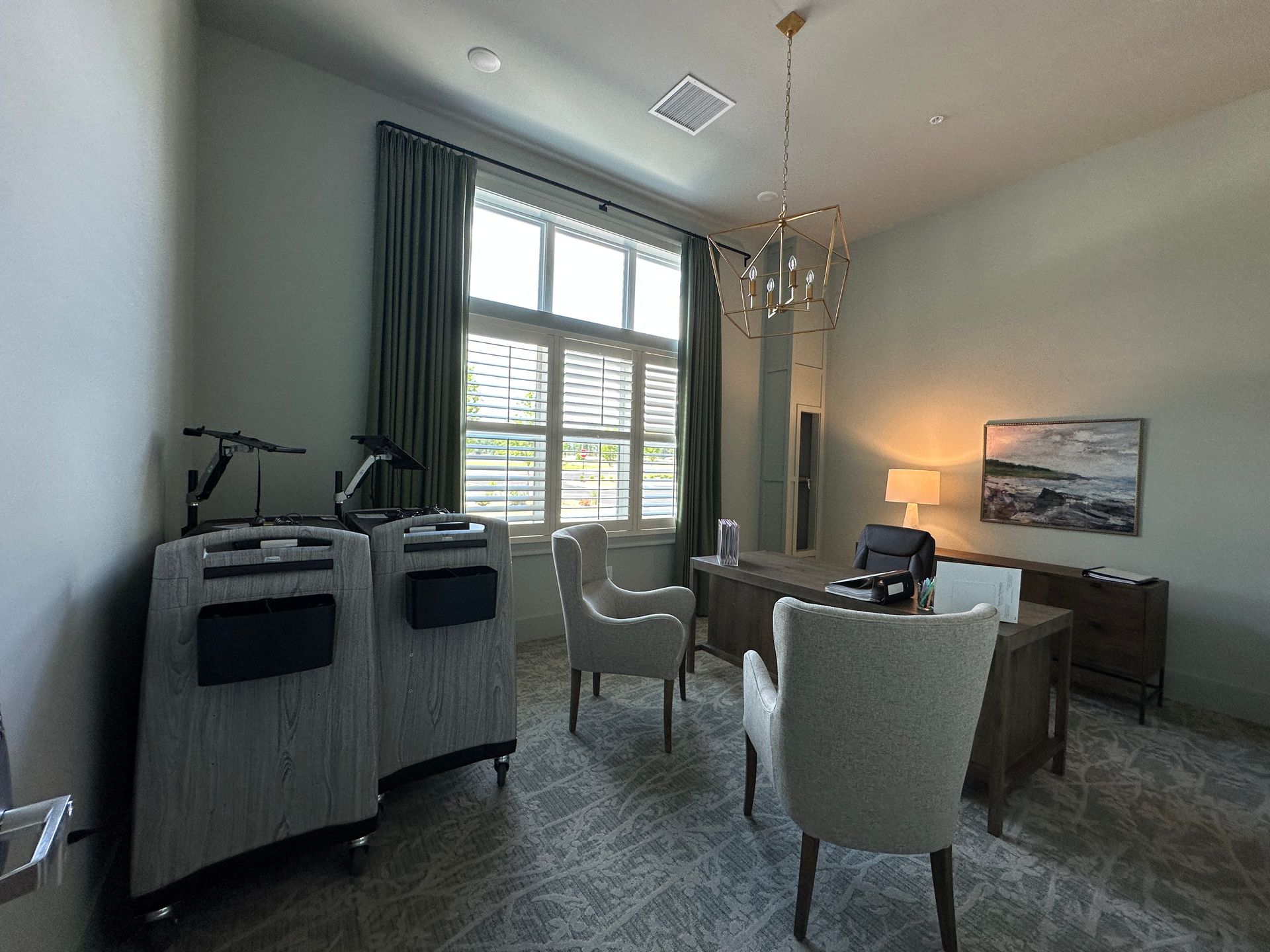 Bright living room with large window, gray chairs, and warm lamp light.