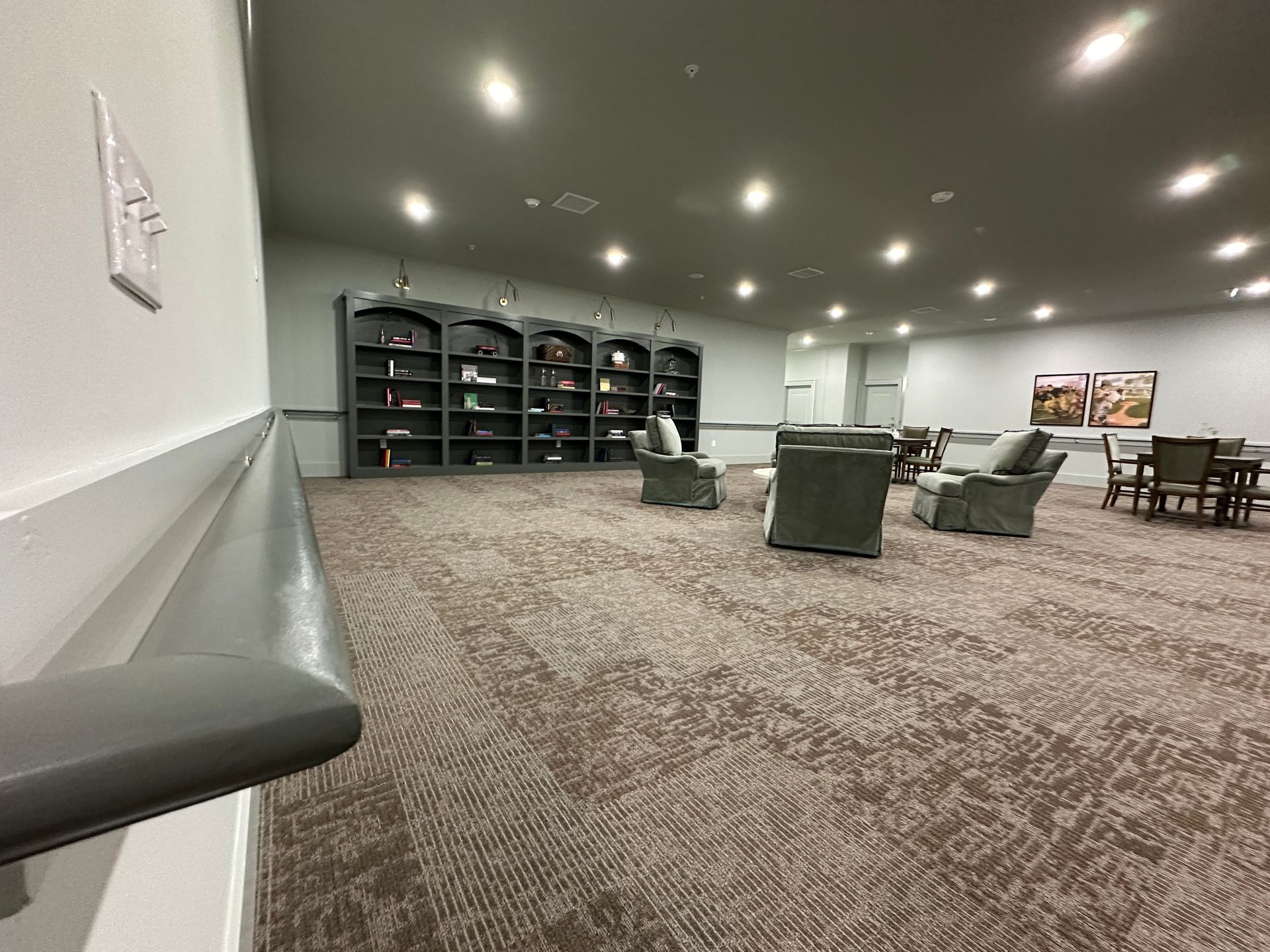 Quiet lounge with carpet, gray chairs, cubbies, and ceiling lights in a spacious room