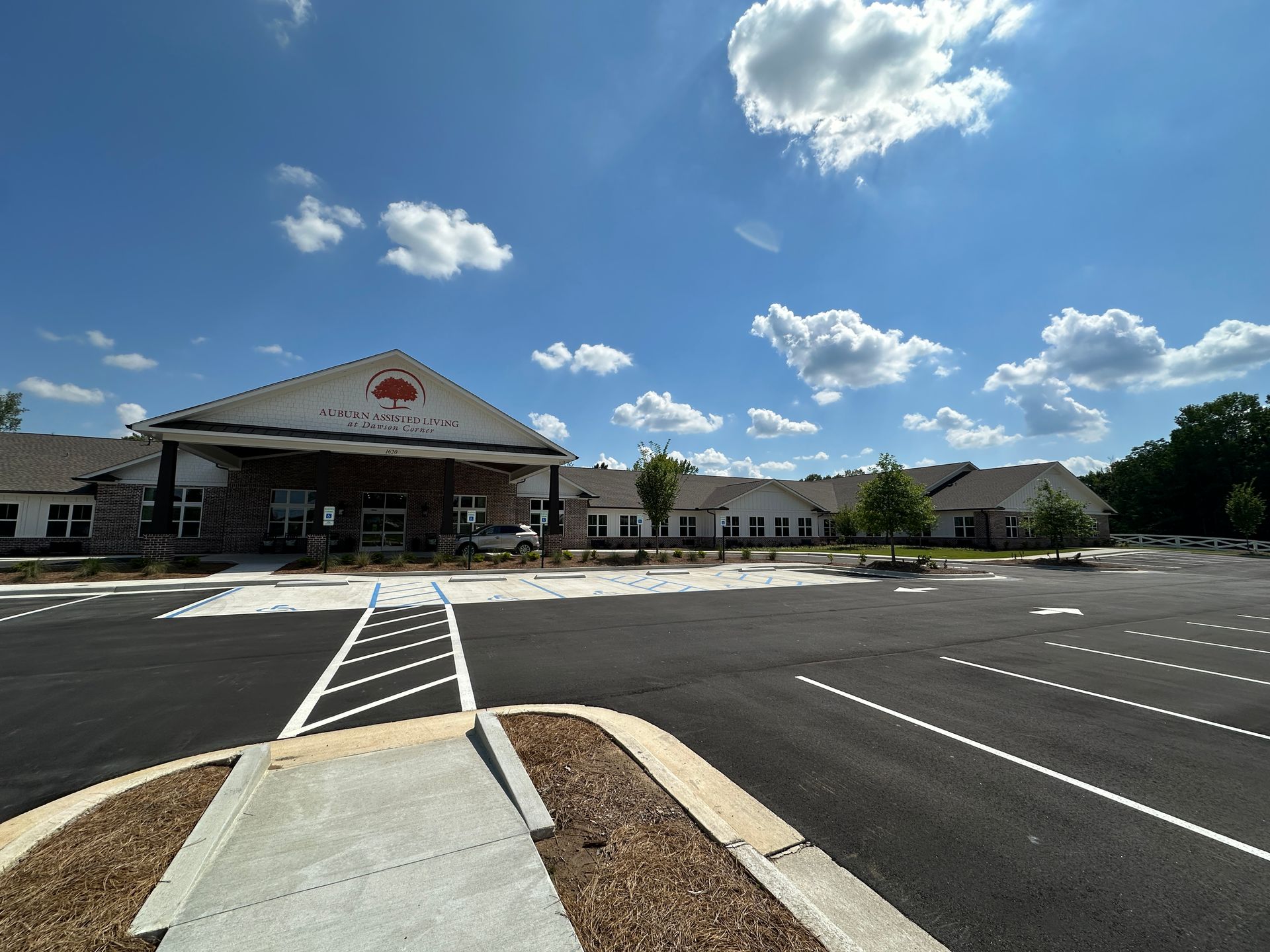 Empty parking lot in front of a large building under a blue sky with scattered clouds