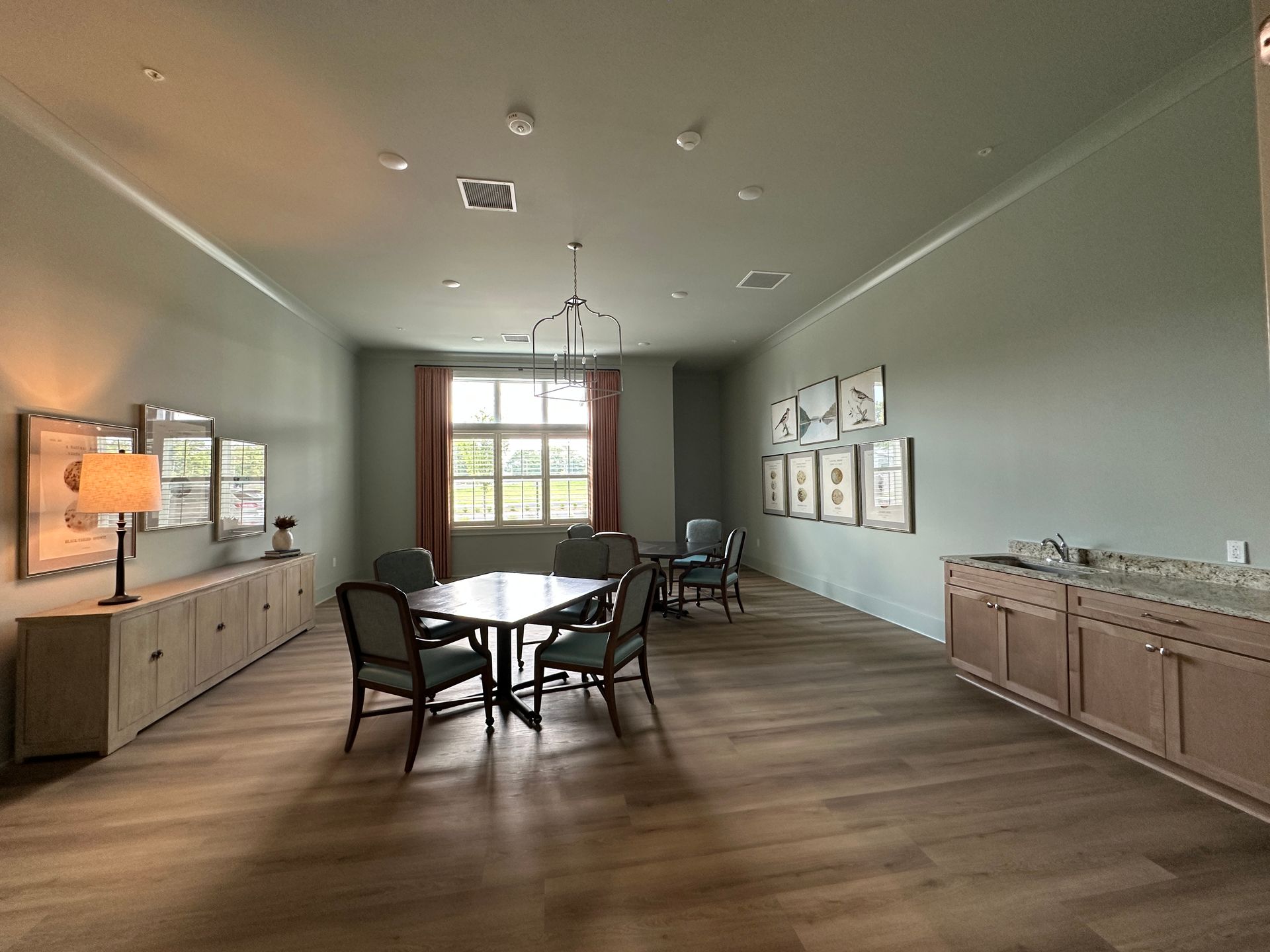 Spacious modern conference room with table and chairs, wood floors, and framed art on the walls.