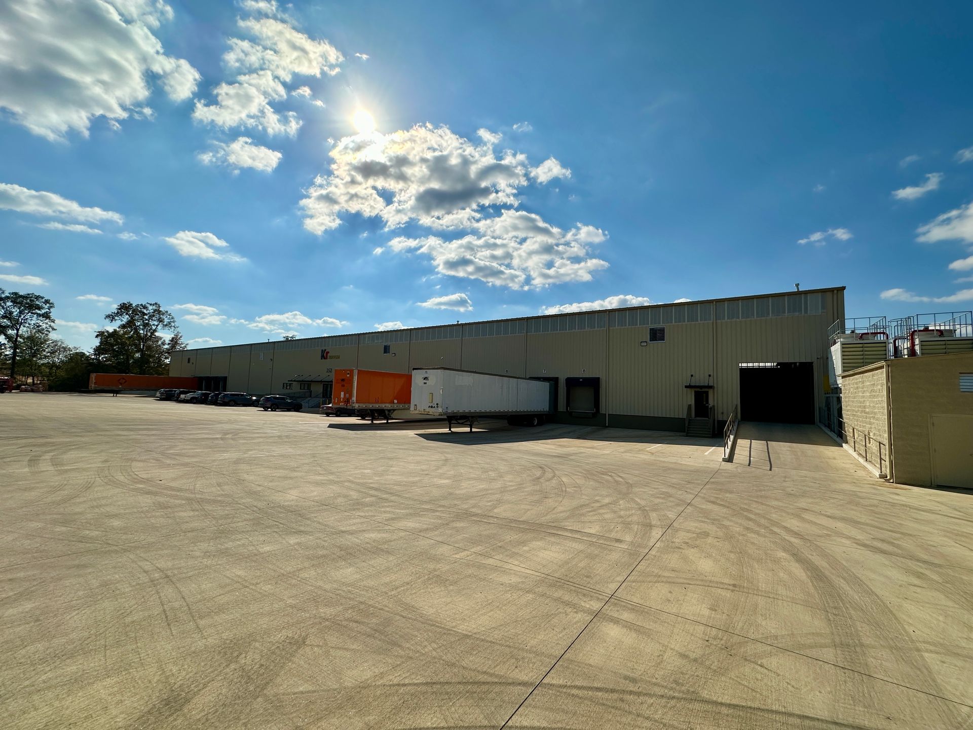 A large warehouse with a lot of trucks parked in front of it.