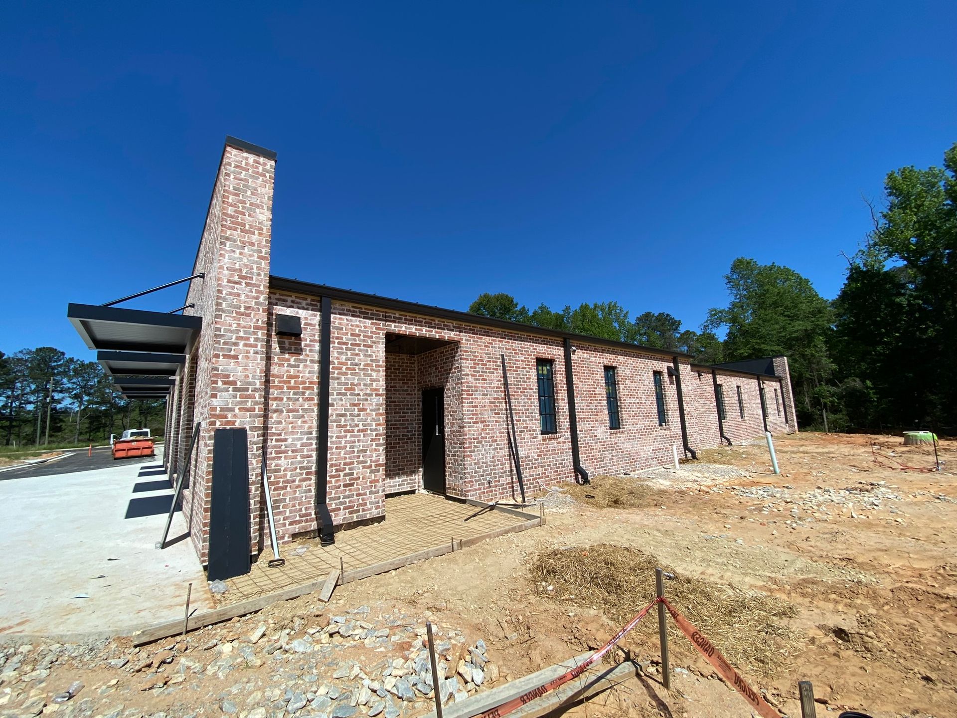 A large brick building is being built in a dirt field.
