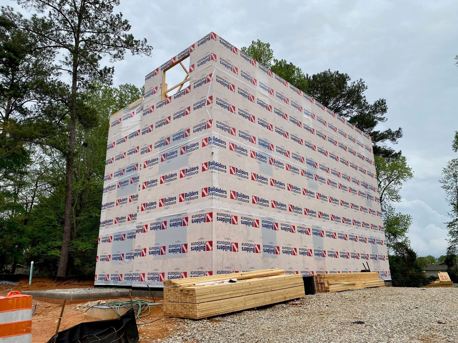 A large building is being built on a gravel road.
