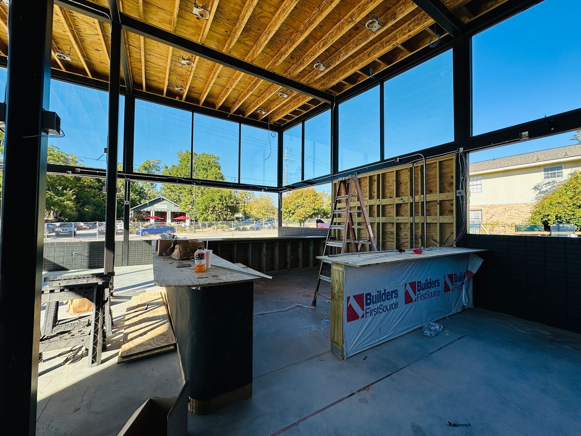 Open-air rooftop bar under construction with exposed wood beams, counters, and a banner-covered table
