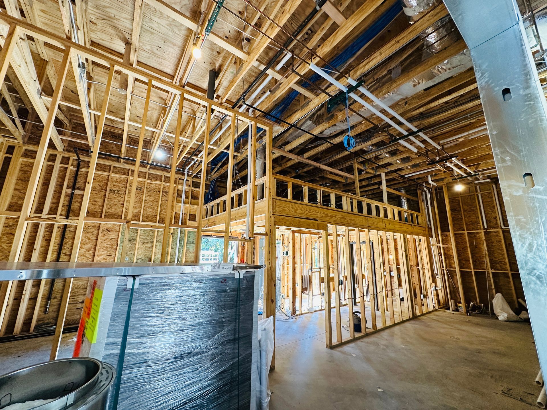 Unfinished restaurant interior with exposed wooden framing, insulation, and concrete floor under construction