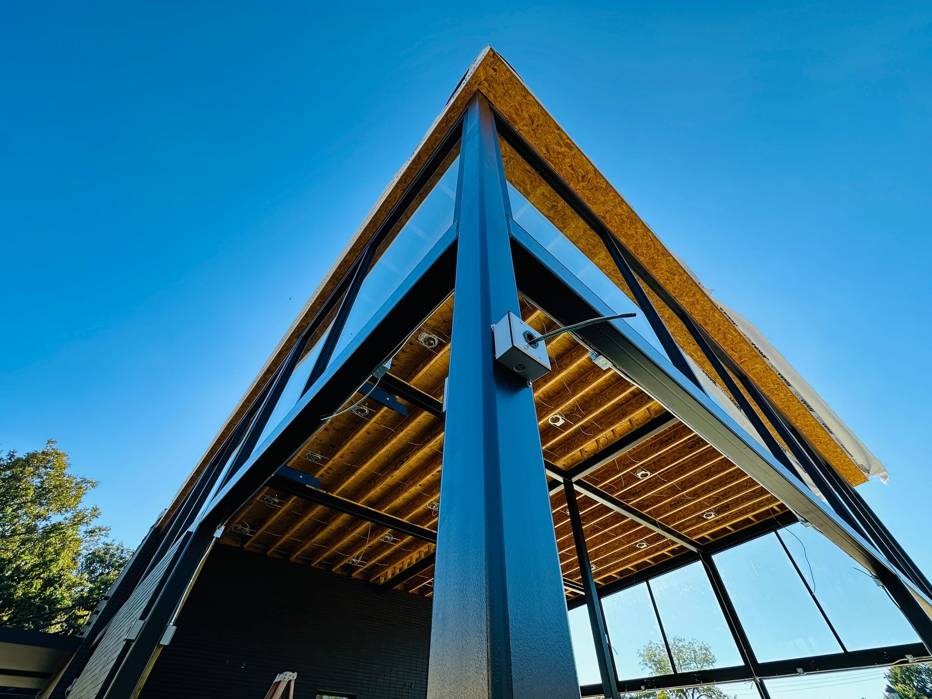 Modern angular building with blue beams and glass panels shot from below against a clear sky