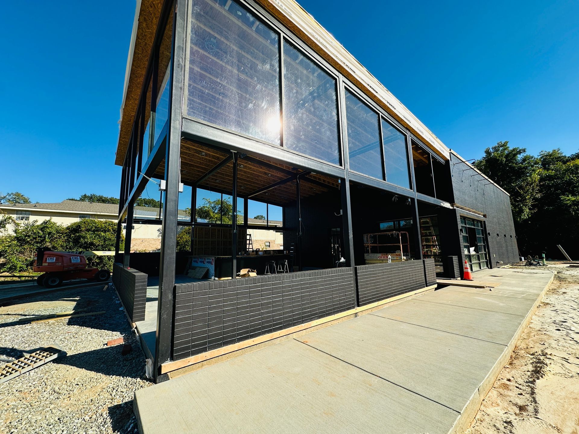 Modern black building with glass panels beside a paved path under a bright blue sky