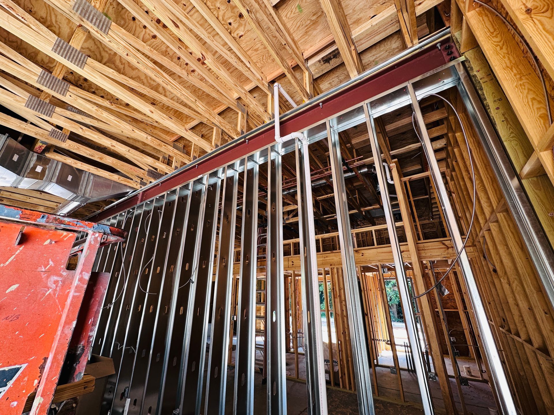 Exposed metal wall studs and wood framing inside a house under construction