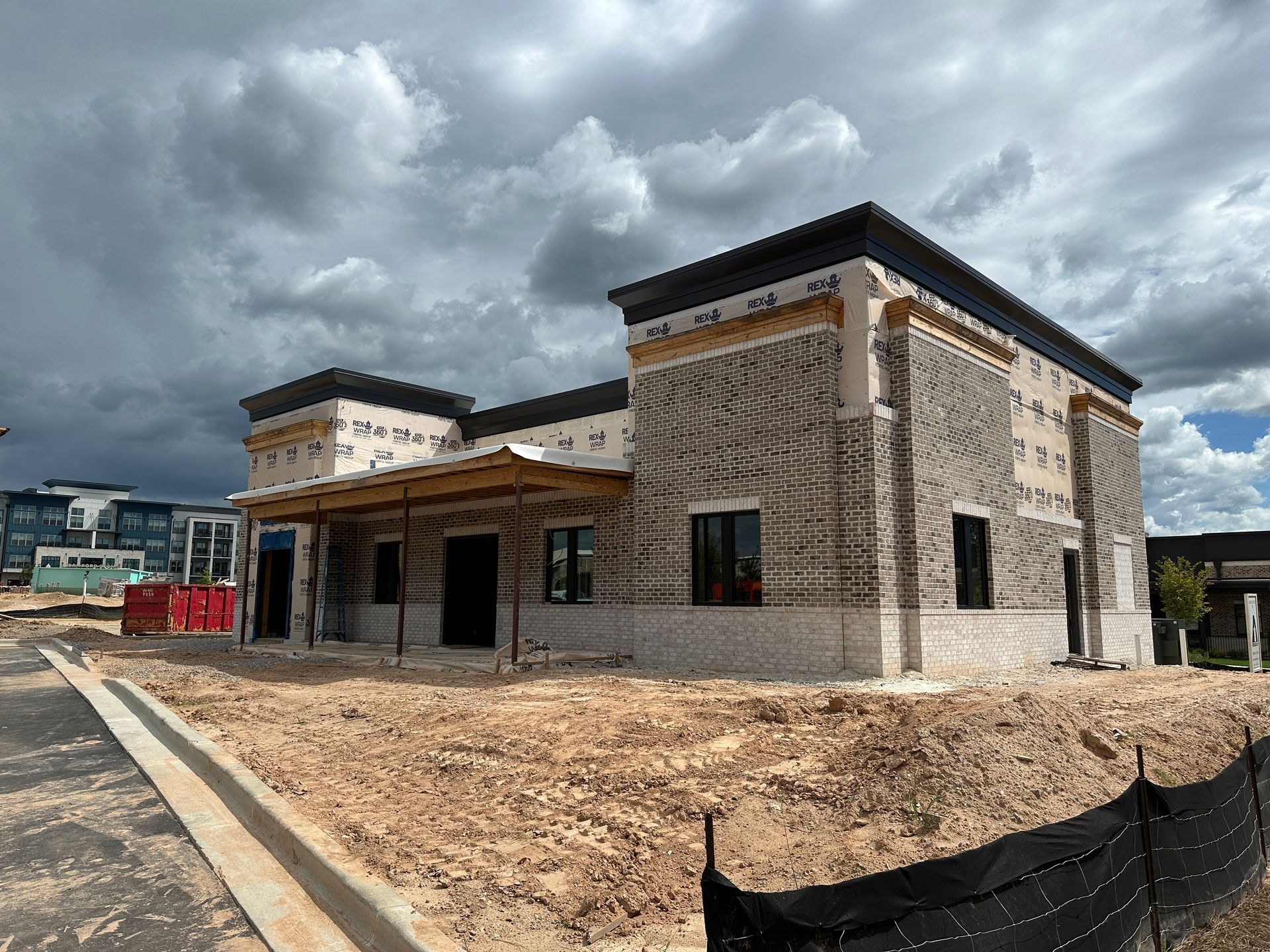 A large brick building is being built in a dirt field.