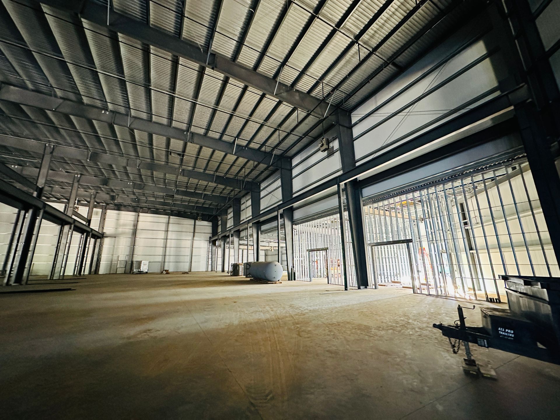 Empty industrial warehouse interior with metal roof trusses and concrete floor