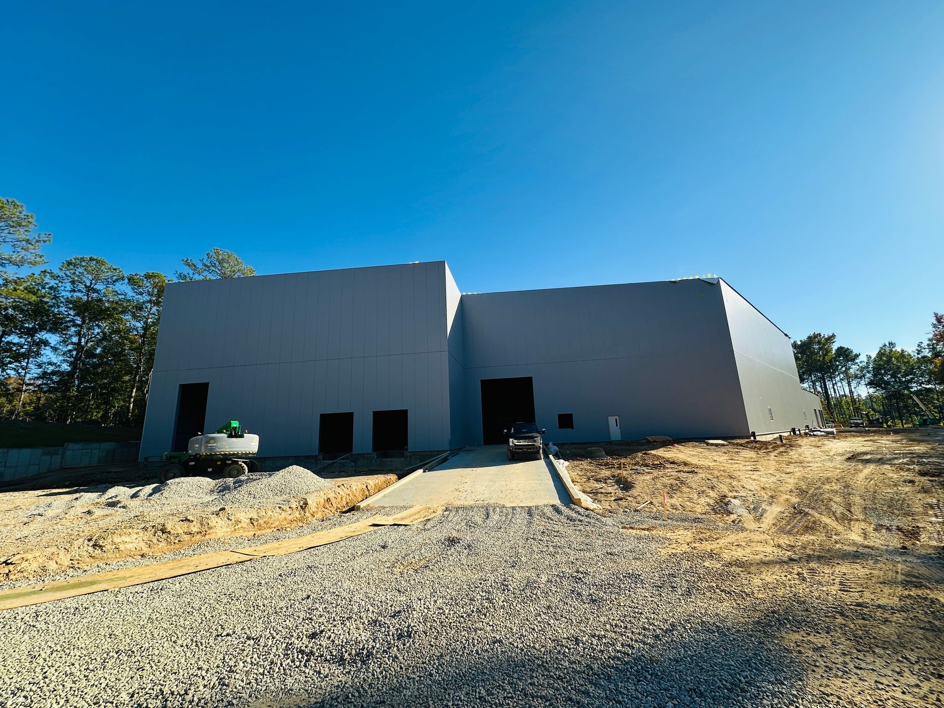 Two unfinished white buildings on a construction site under a clear blue sky