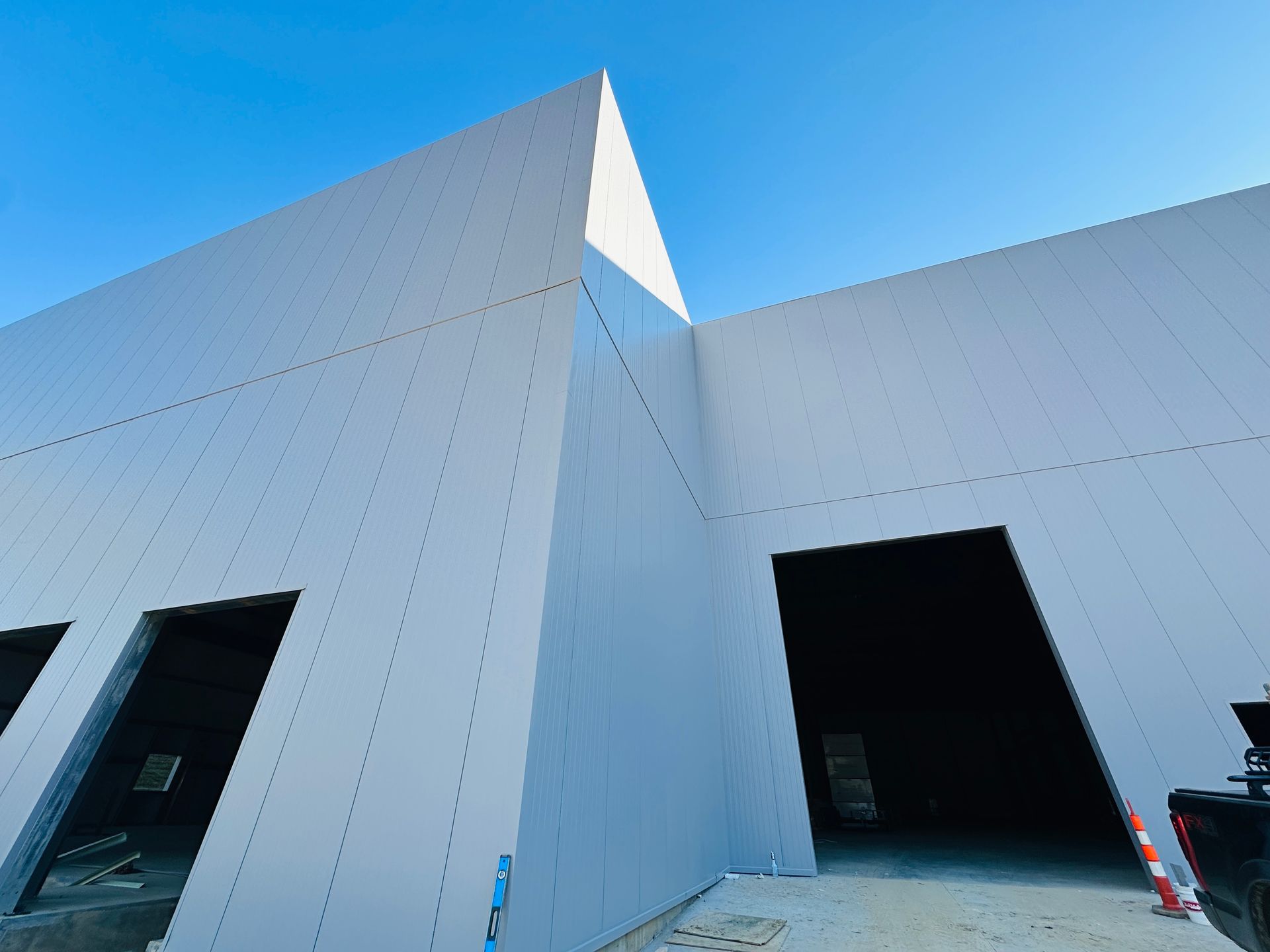 Modern white building with tall angular walls and open doorways under a blue sky