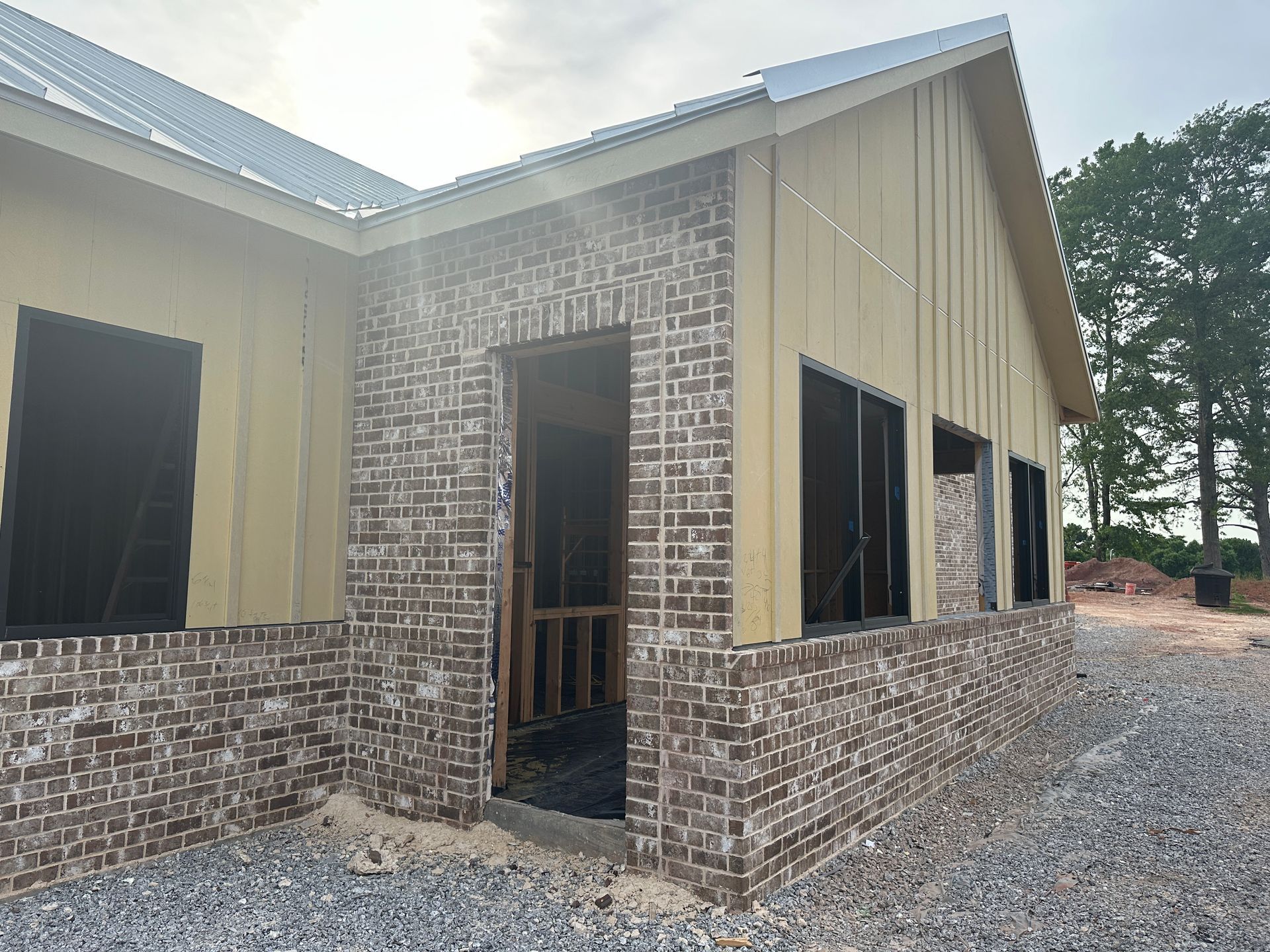 A building under construction with a brick wall and a metal roof.