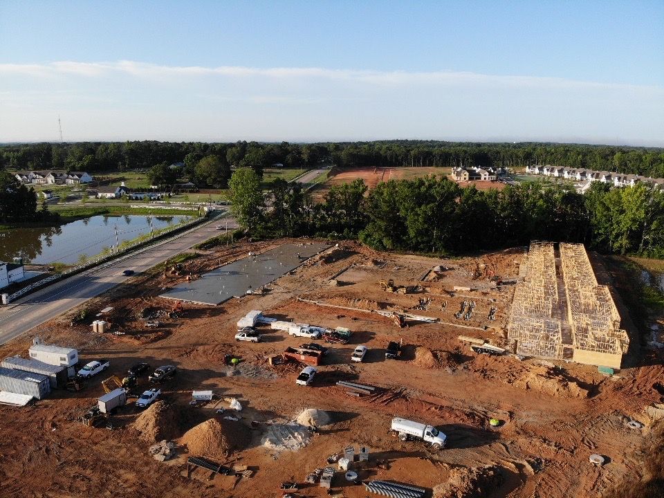 An aerial view of a construction site with trucks and trees in the background