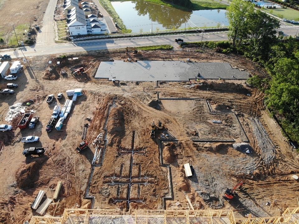 An aerial view of a construction site with a pond in the background.